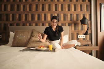 A woman sitting on a bed in a hotel room