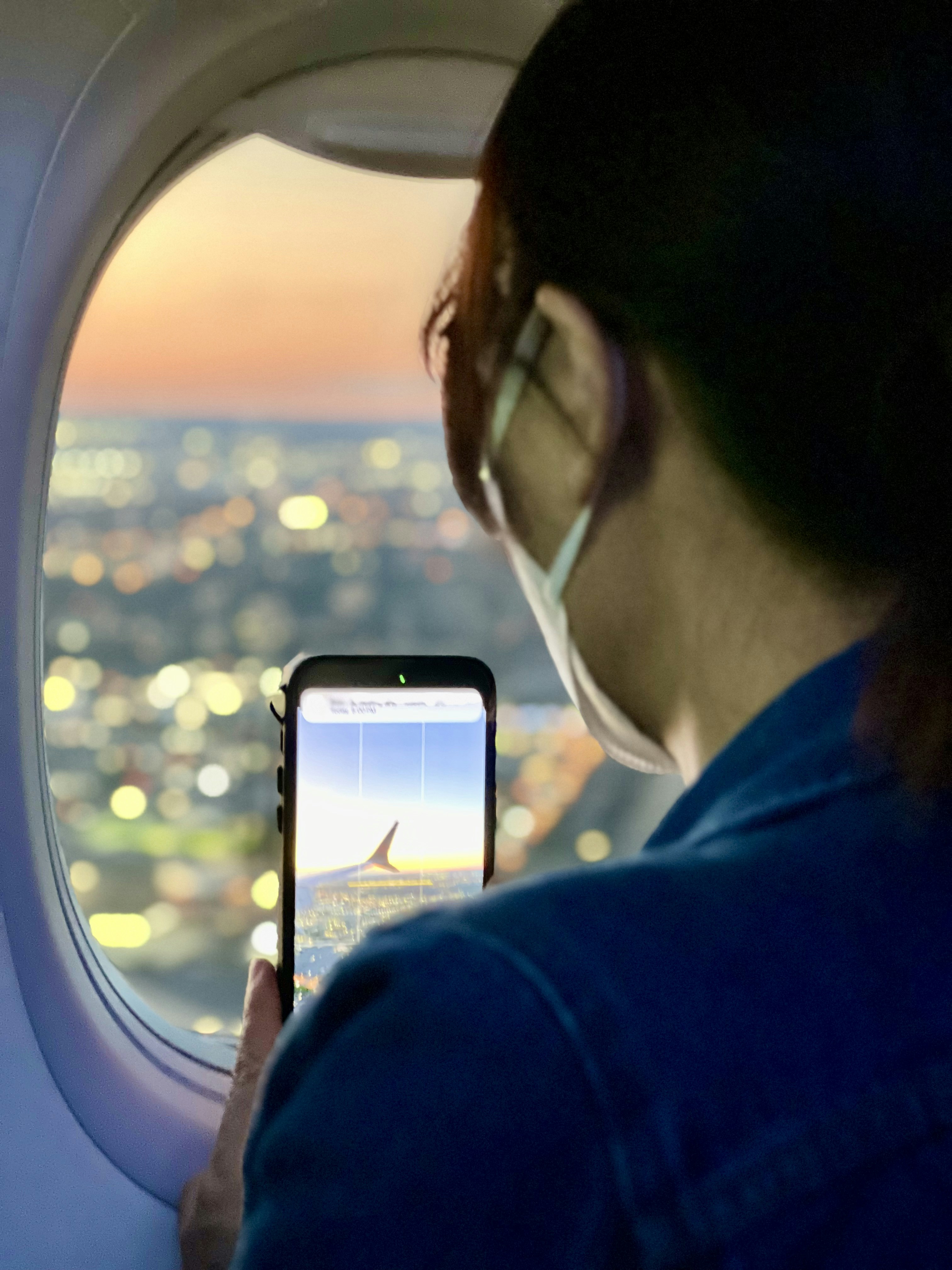 A woman looking out an airplane window at the view of the city