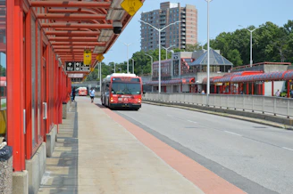 A red and white bus and some buildings and trees
