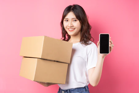 A woman holding a box and a cell phone