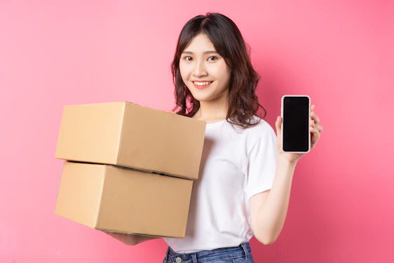 A woman holding a box and a cell phone