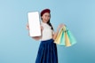 A woman holding a tablet computer and shopping bags