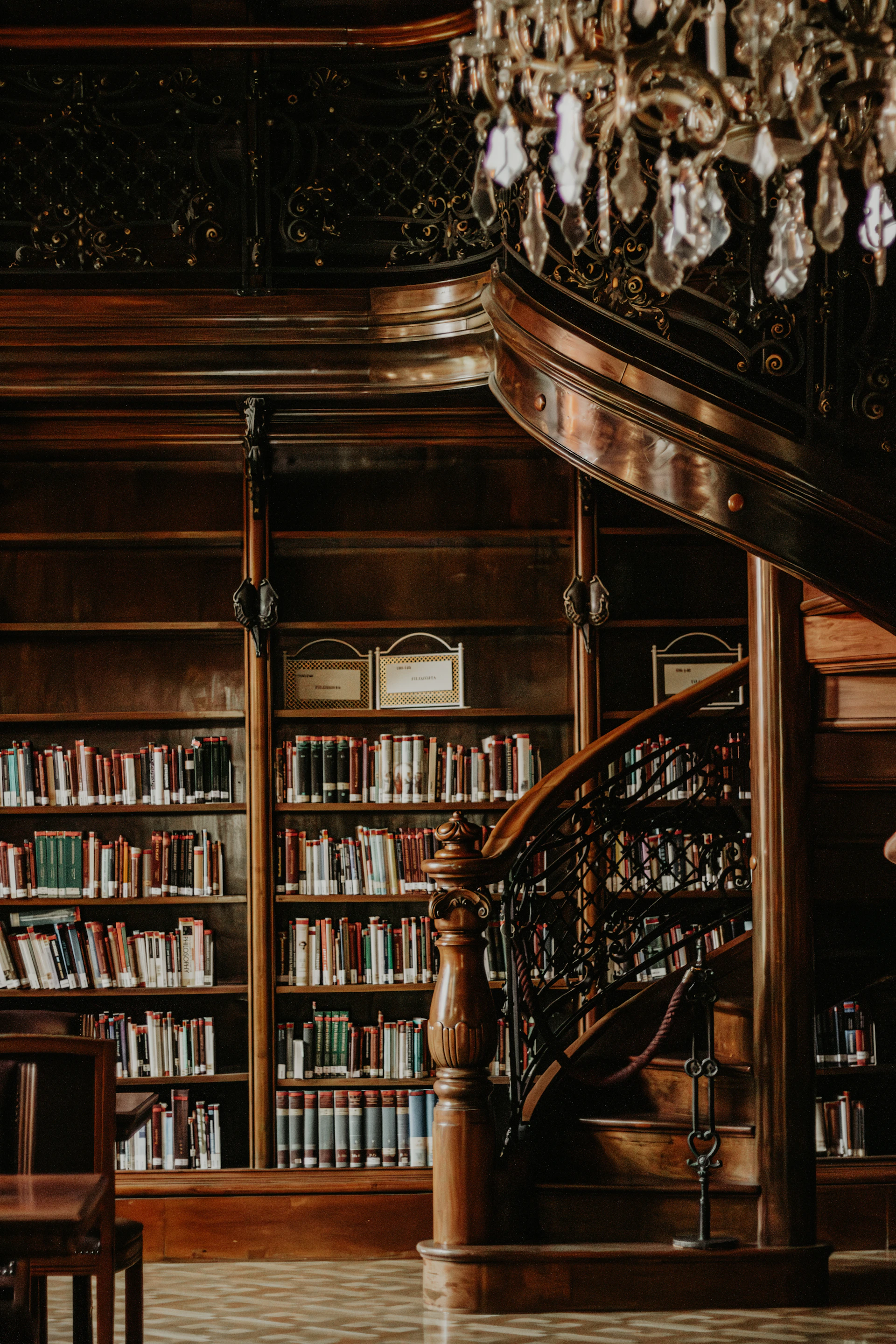 A staircase in a library with a chandelier hanging from the ceiling