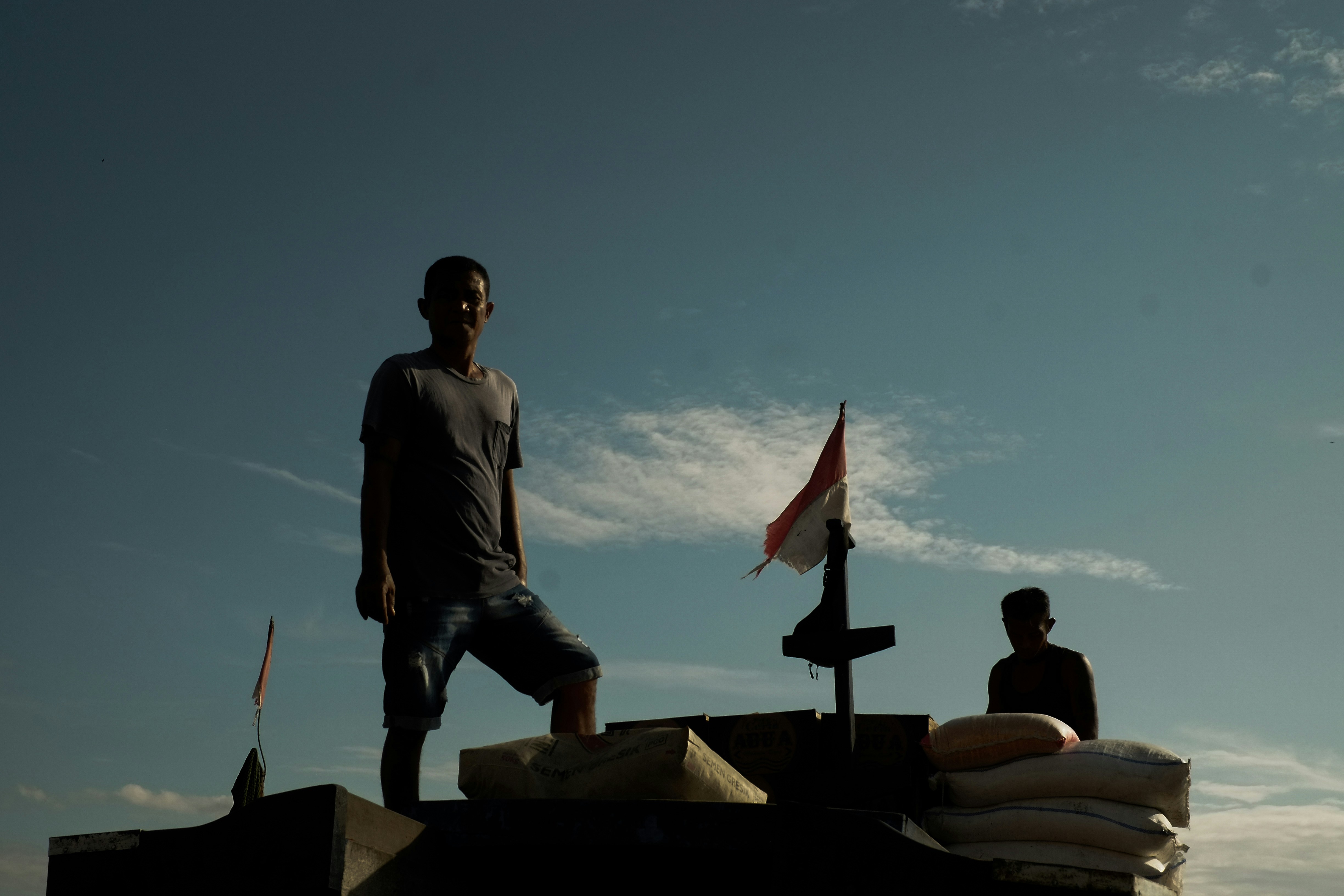 Seorang pria berdiri di atas atap di sebelah bendera