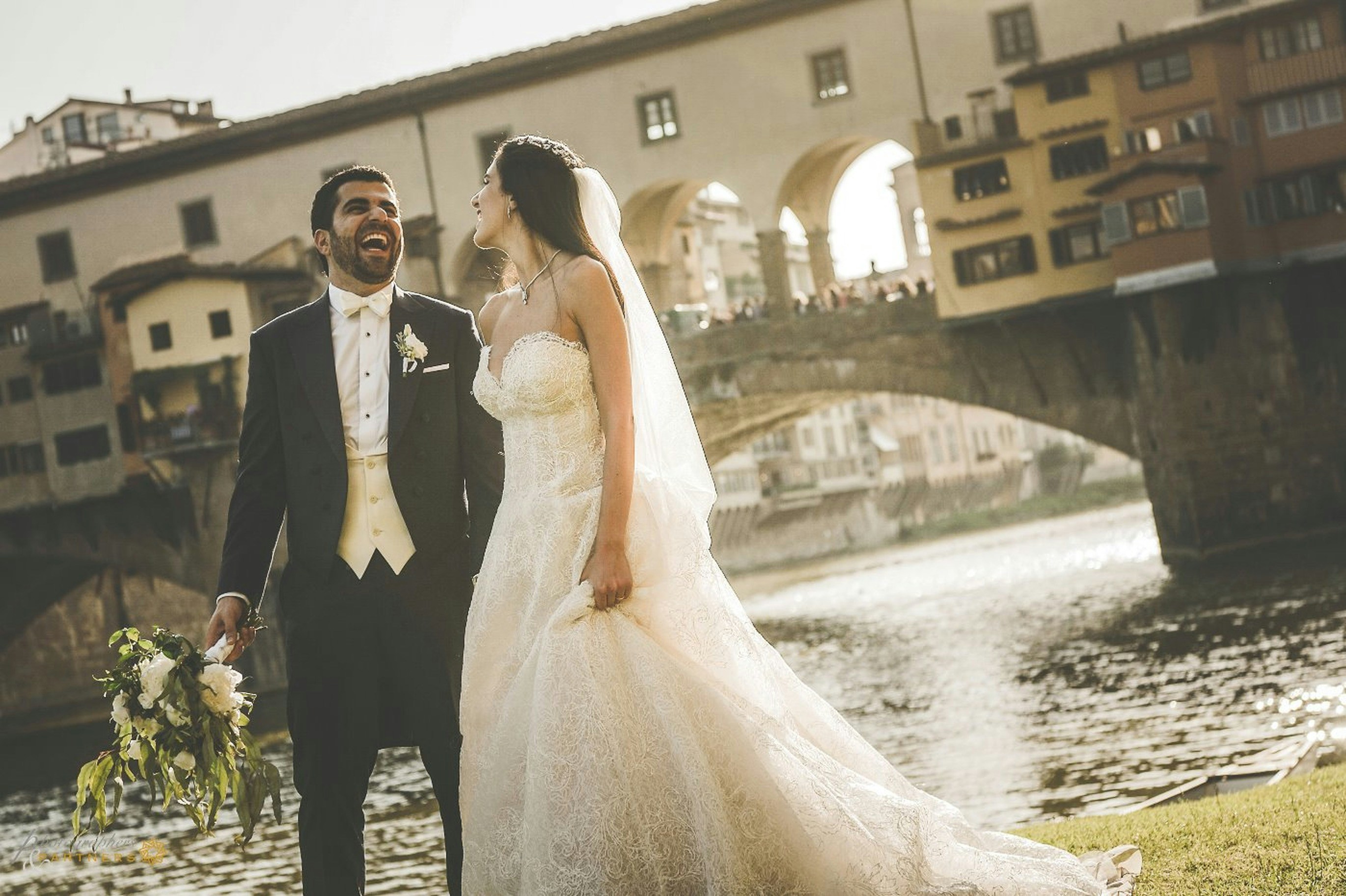 A bride and groom standing in front of a river