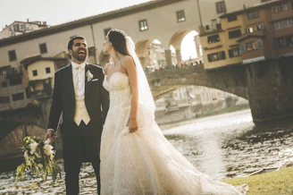 A bride and groom standing in front of a river