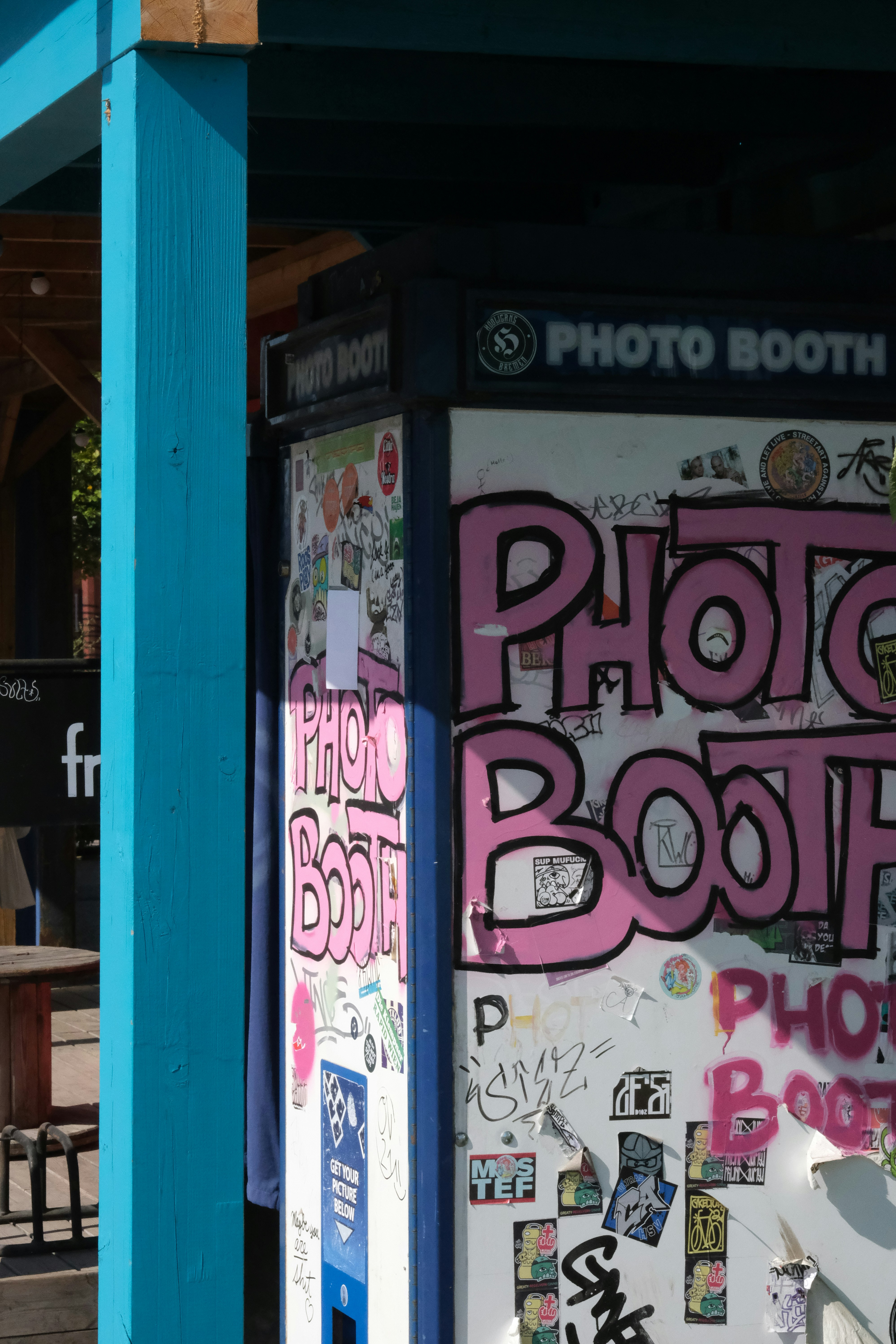 A photo booth is covered in graffiti and stickers
