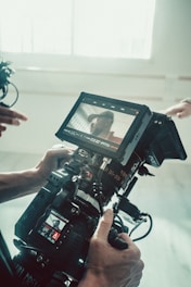 A person holding a camera in front of a window