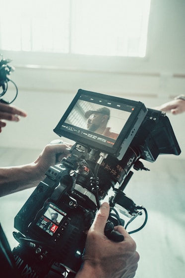 A person holding a camera in front of a window