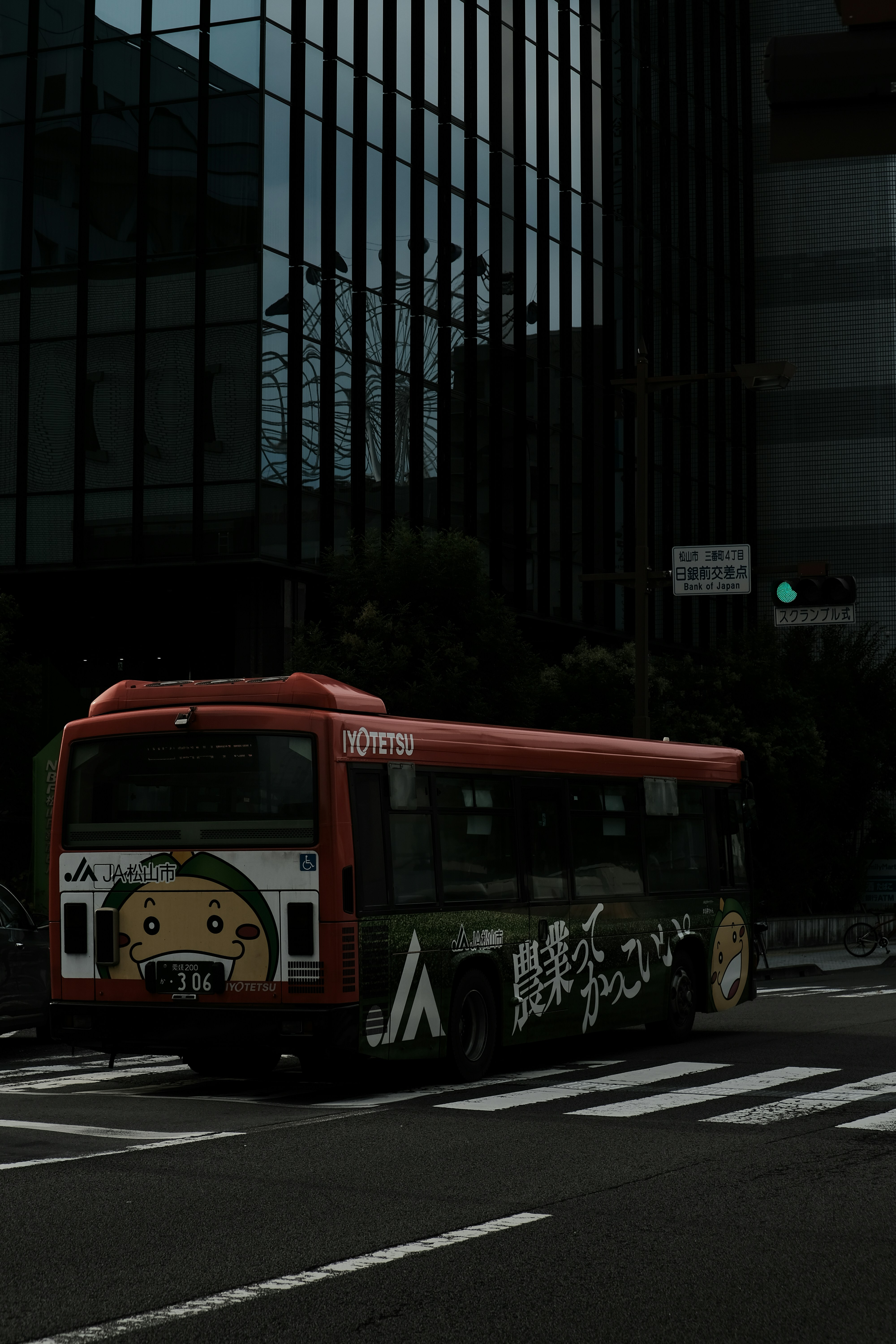 A red bus driving down a street next to tall buildings