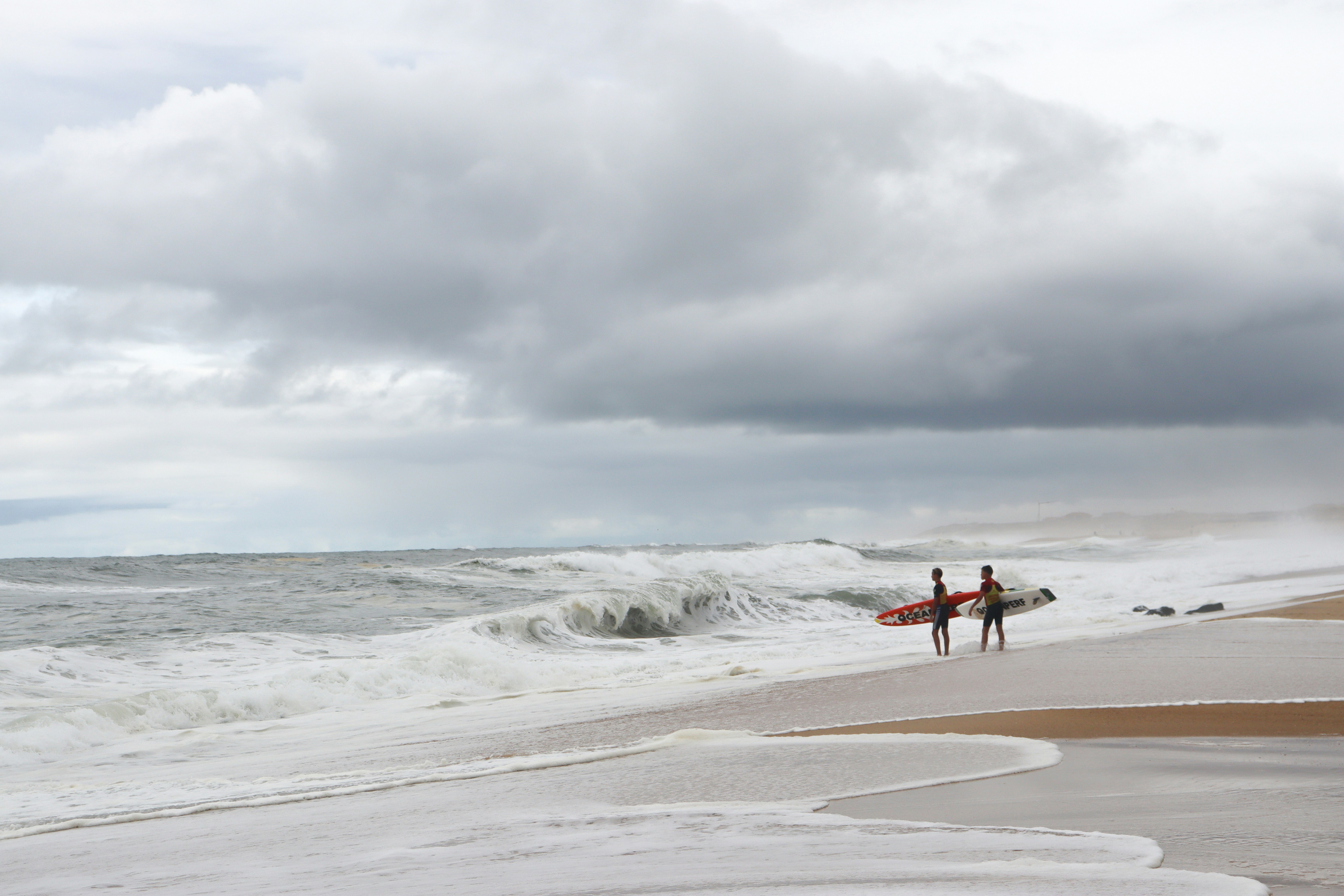 海の隣のビーチの上に立っている数人の人々