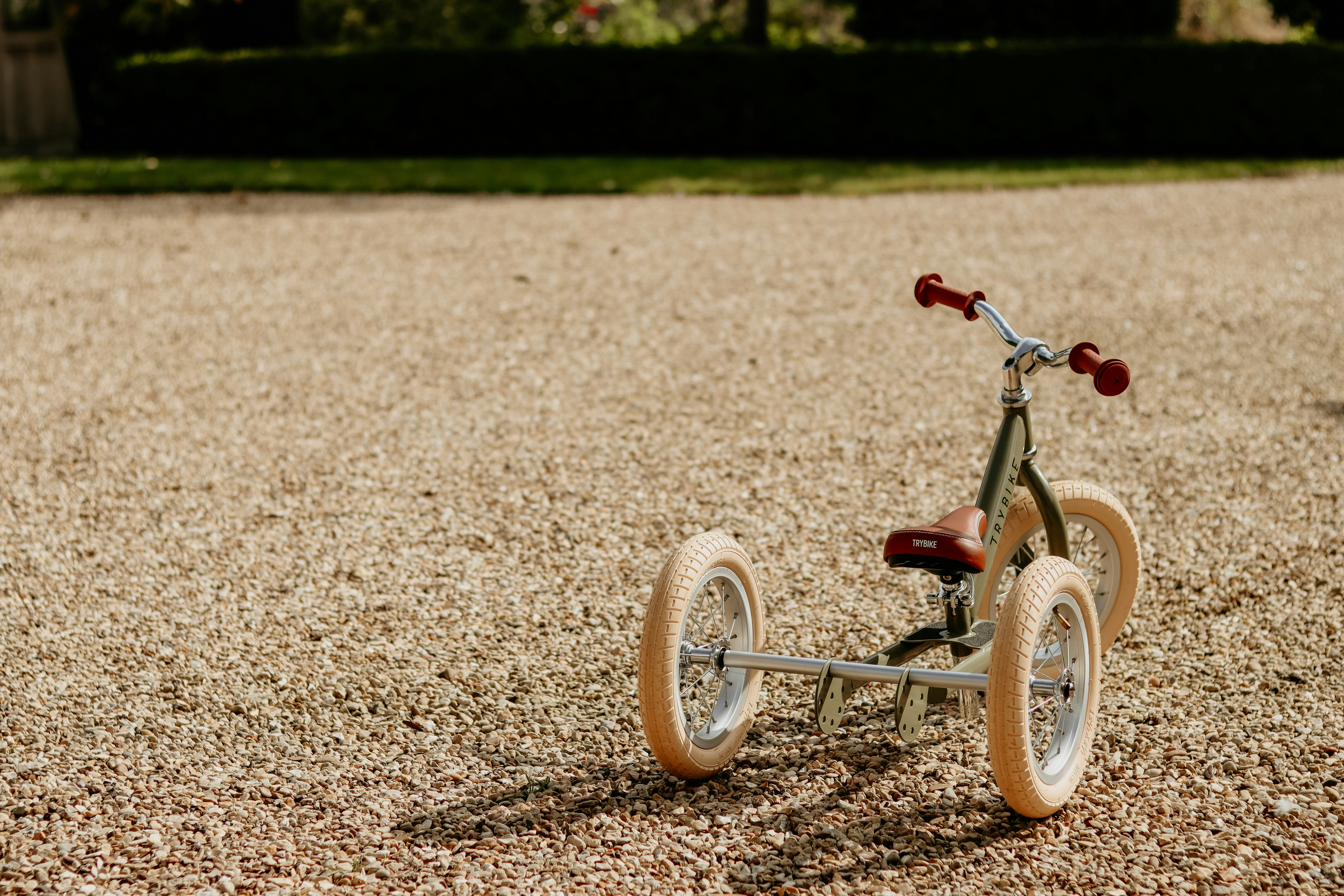 A small tricycle sitting on top of a gravel field
