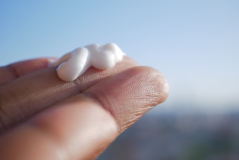 A hand holding a small piece of marshmallow