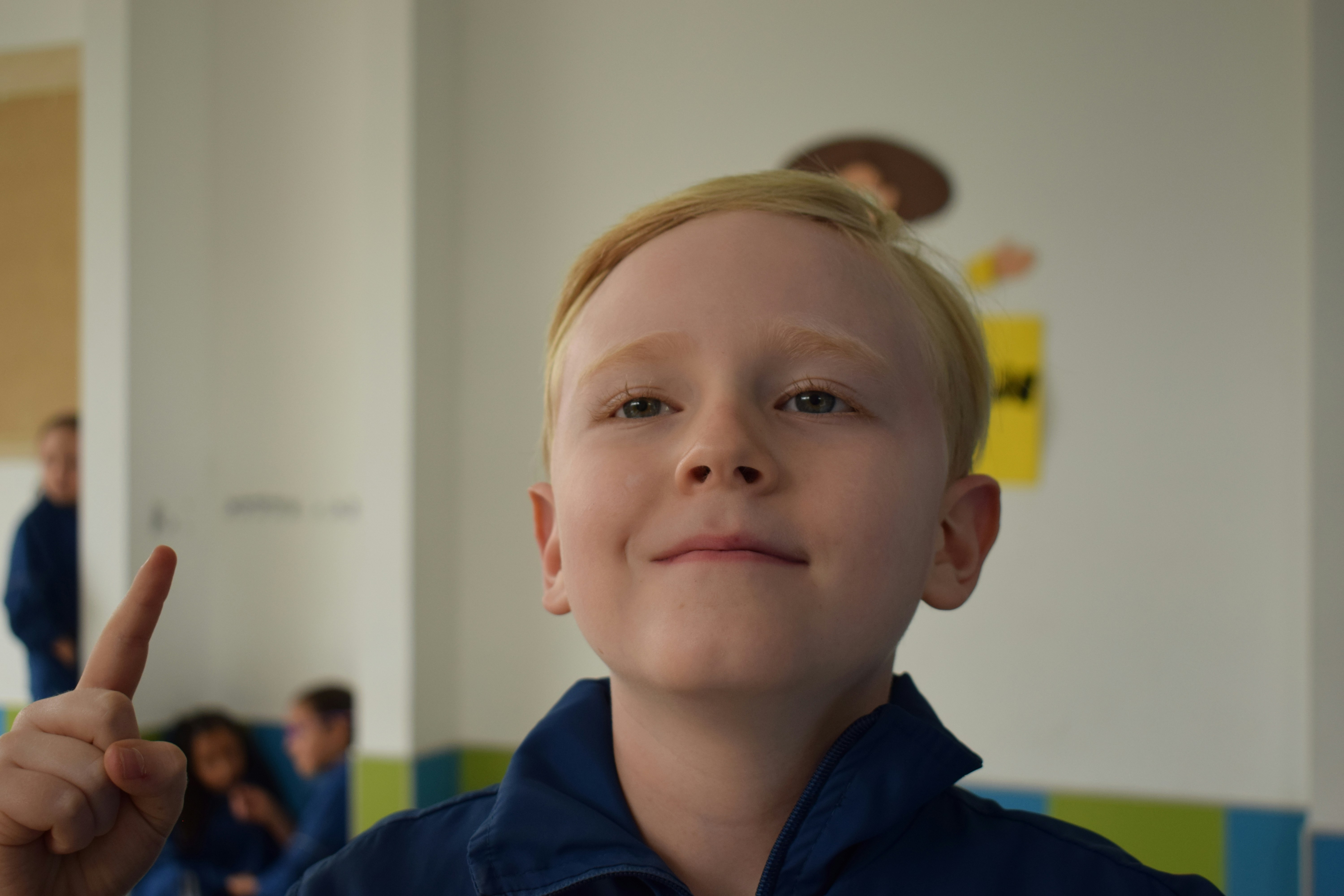 A young boy in a blue shirt pointing at something