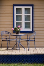 A patio with a table and chairs next to a window