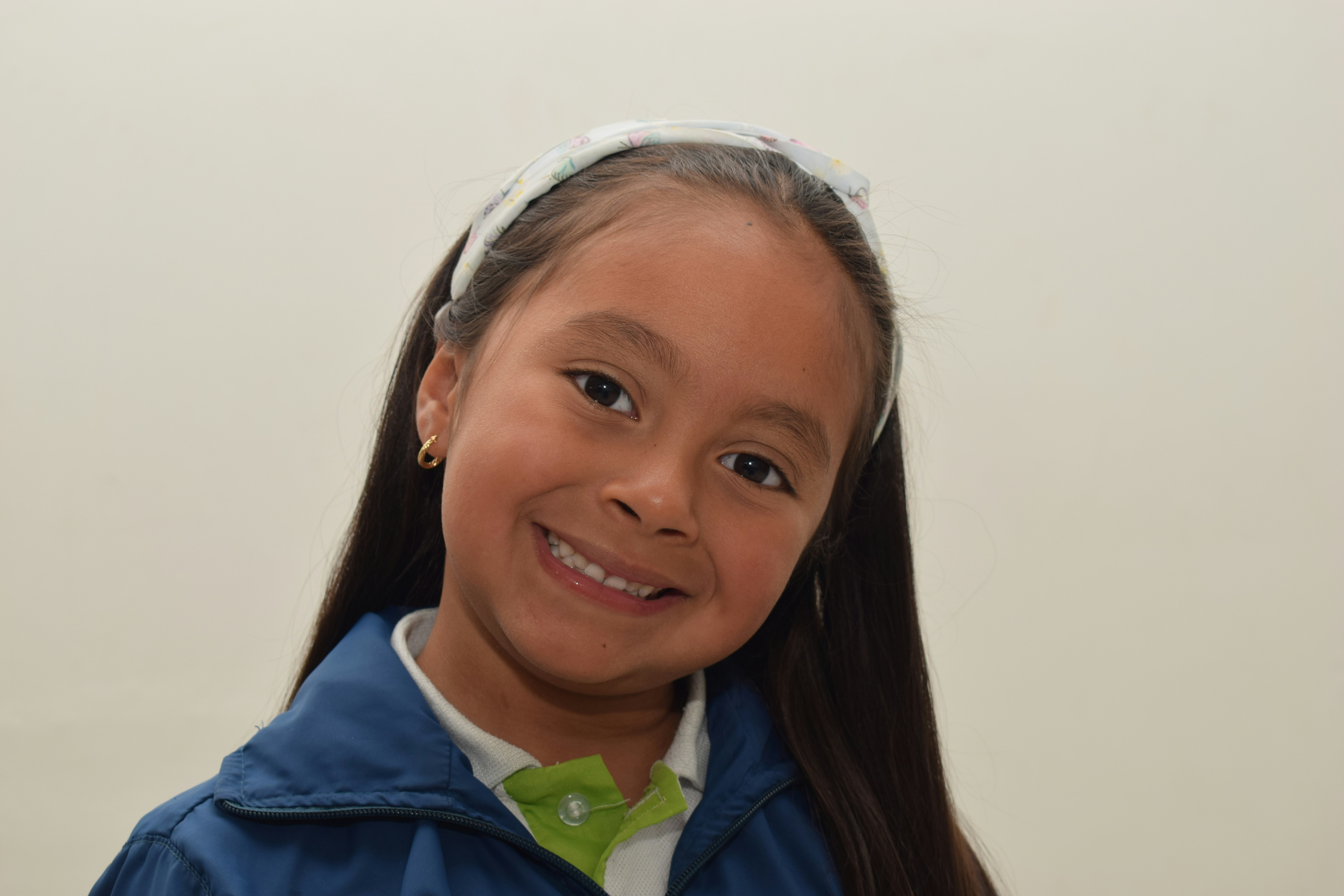A young girl wearing a blue jacket and green bow tie