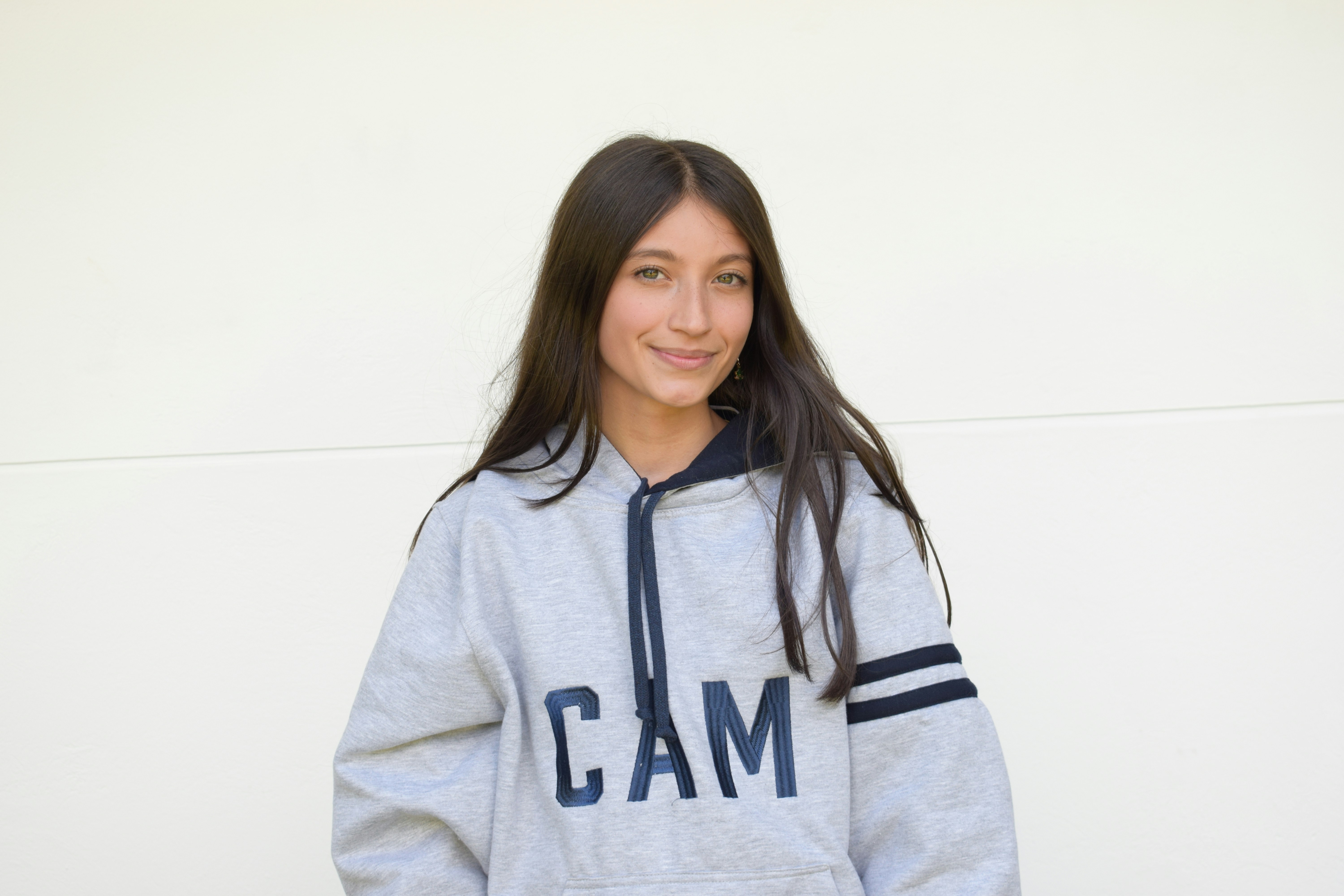 A young girl wearing a gray sweatshirt with the word cam on it
