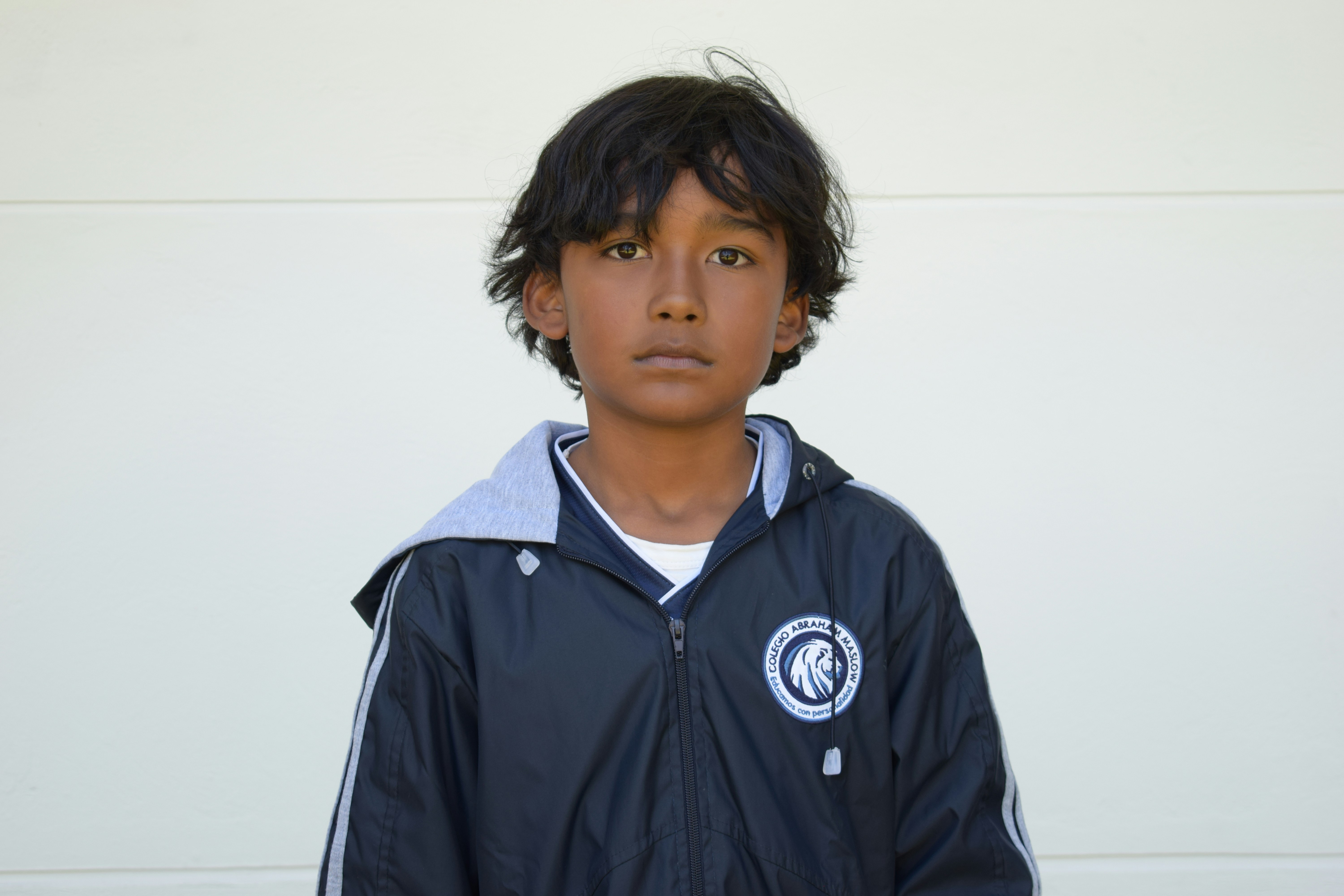 A young boy standing in front of a white wall