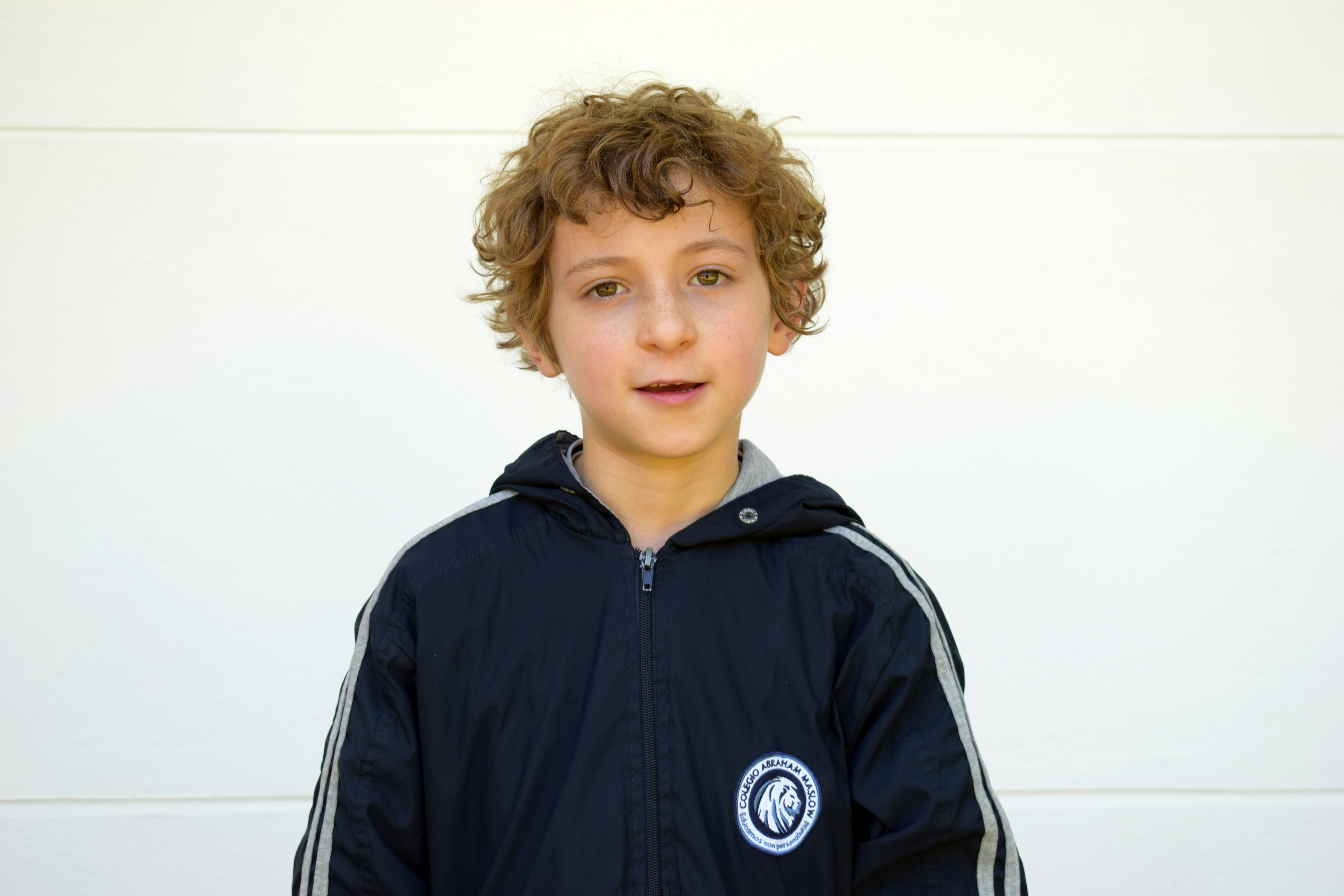 A young boy in a blue jacket holding a tennis racquet