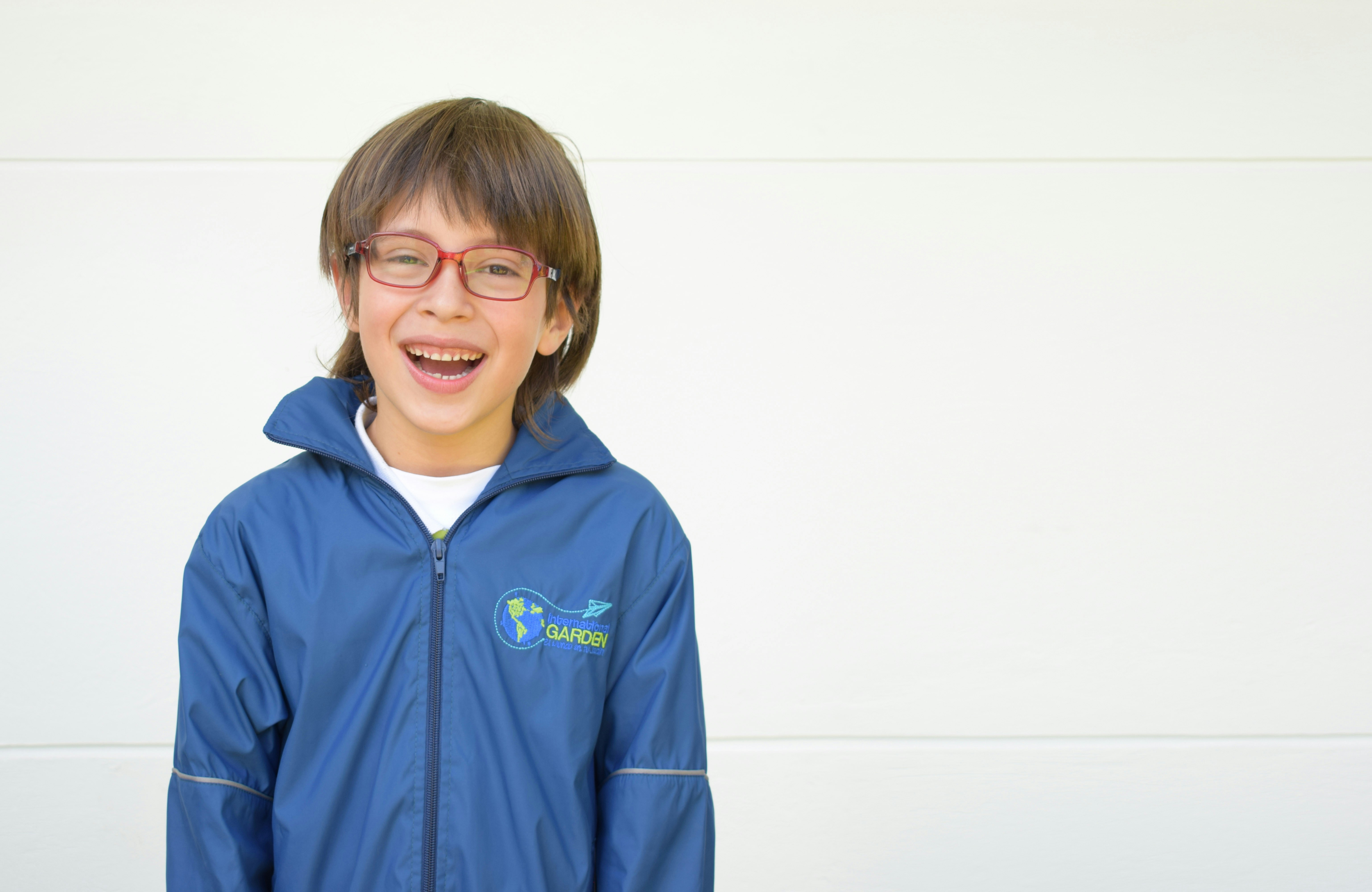 A young boy wearing glasses and a blue jacket