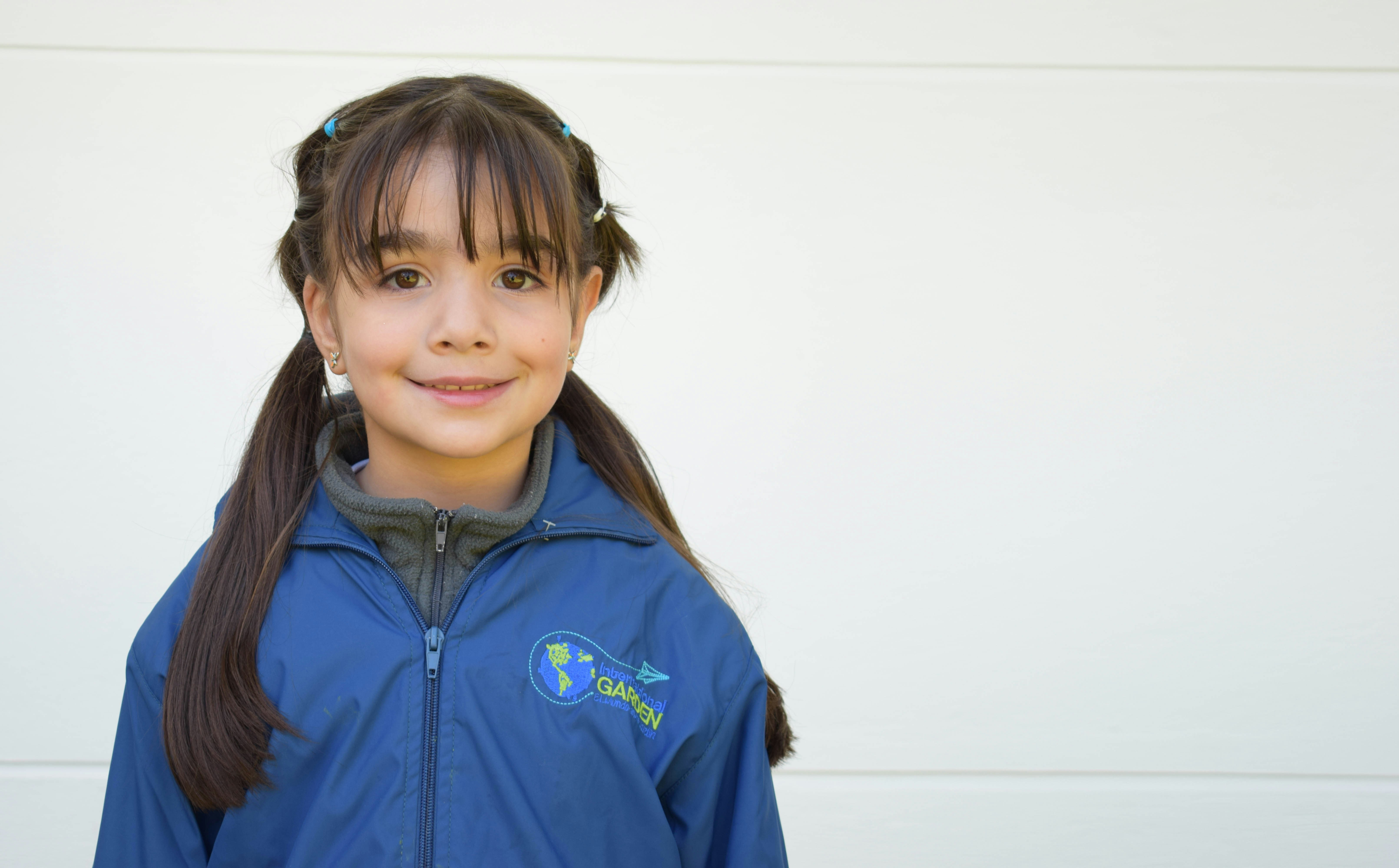 A young girl wearing a blue jacket and a ponytail