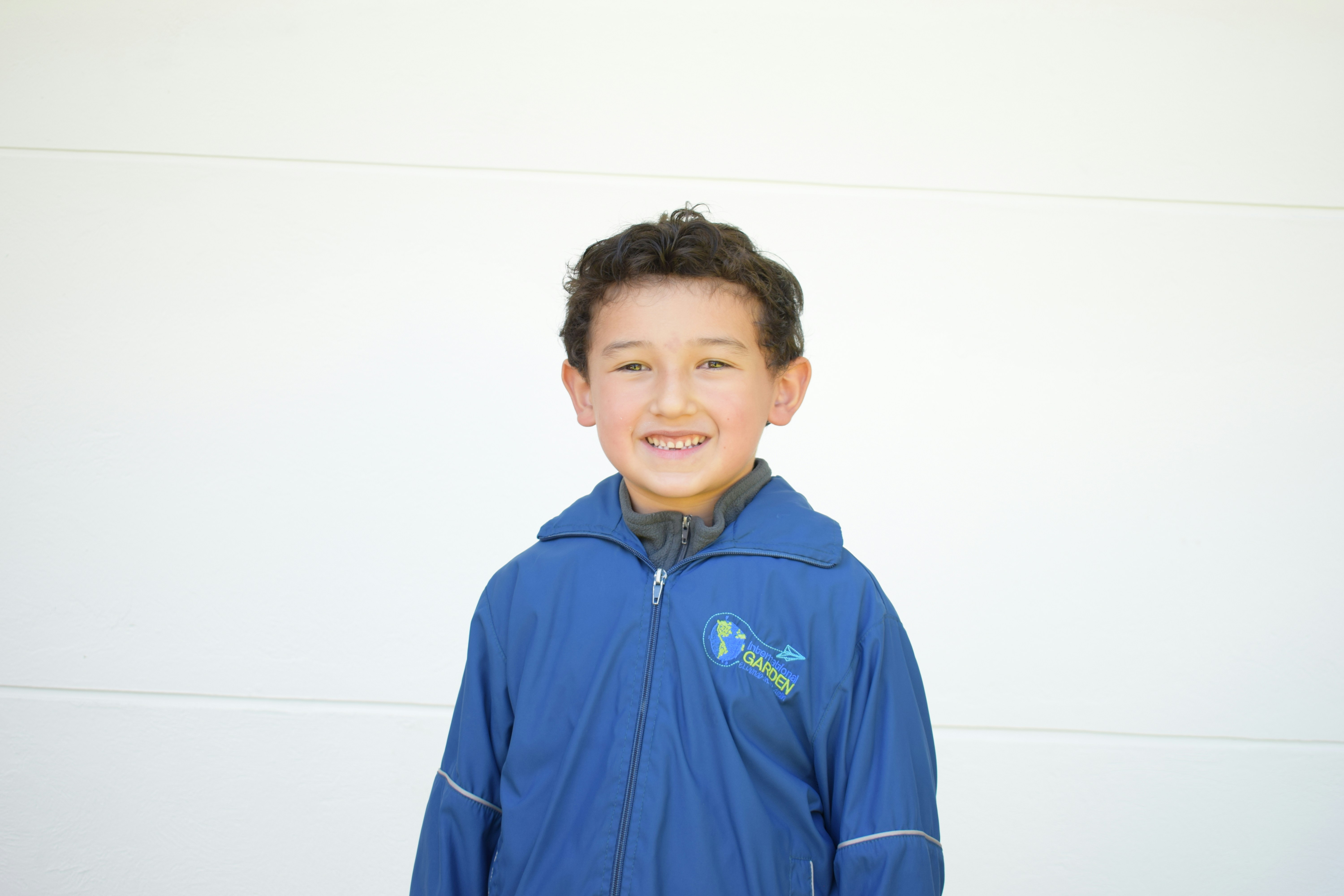 A young boy standing in front of a white wall