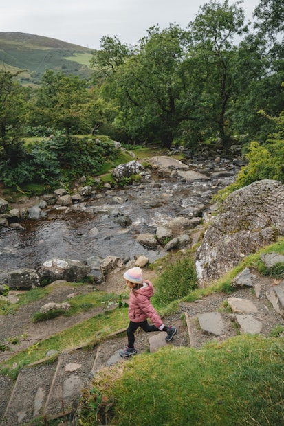 A little girl walking up a set of steps next to a river