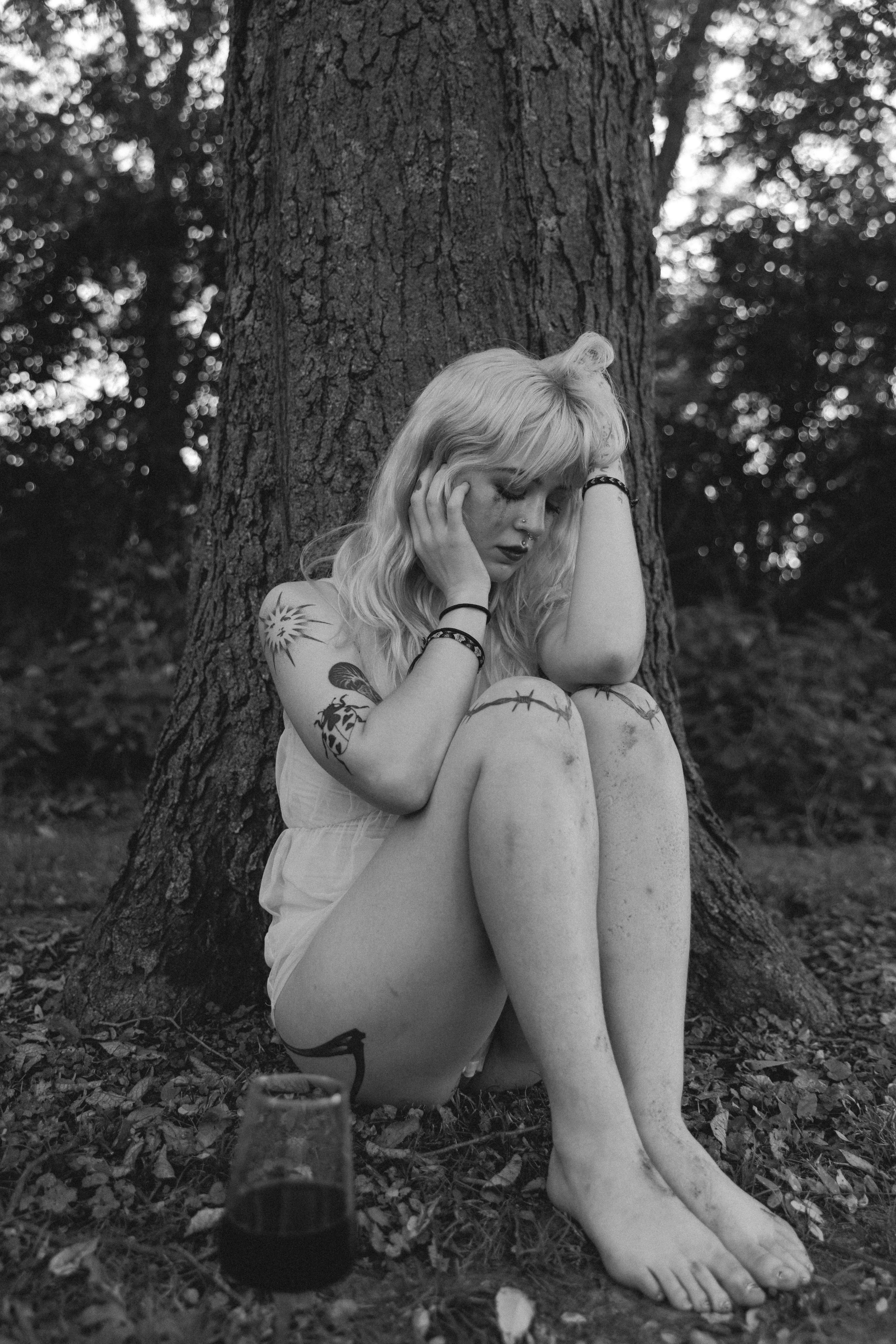 A woman sitting on the ground next to a tree