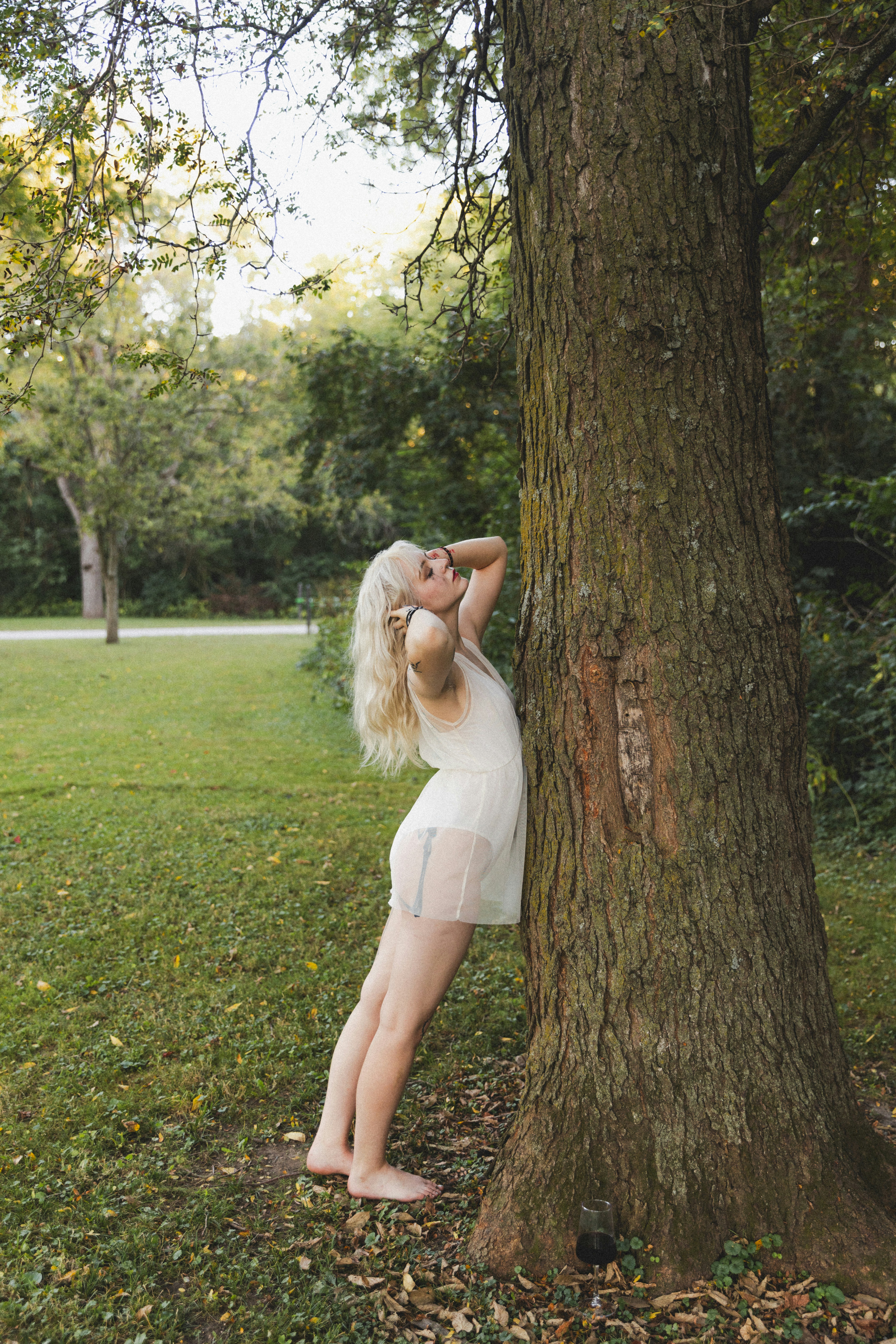A woman leaning against a tree in a park