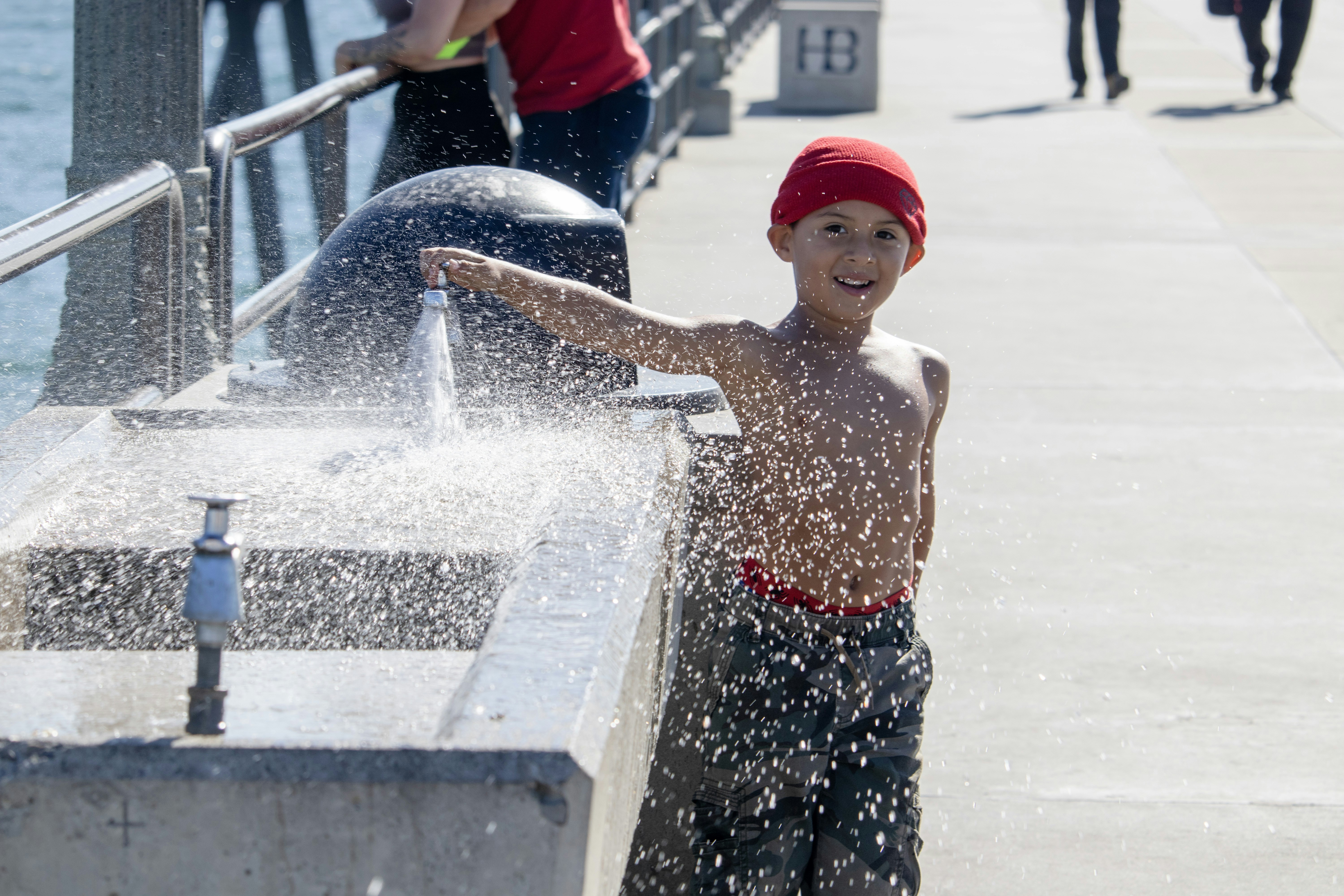 Un niño de pie junto a una fuente de agua