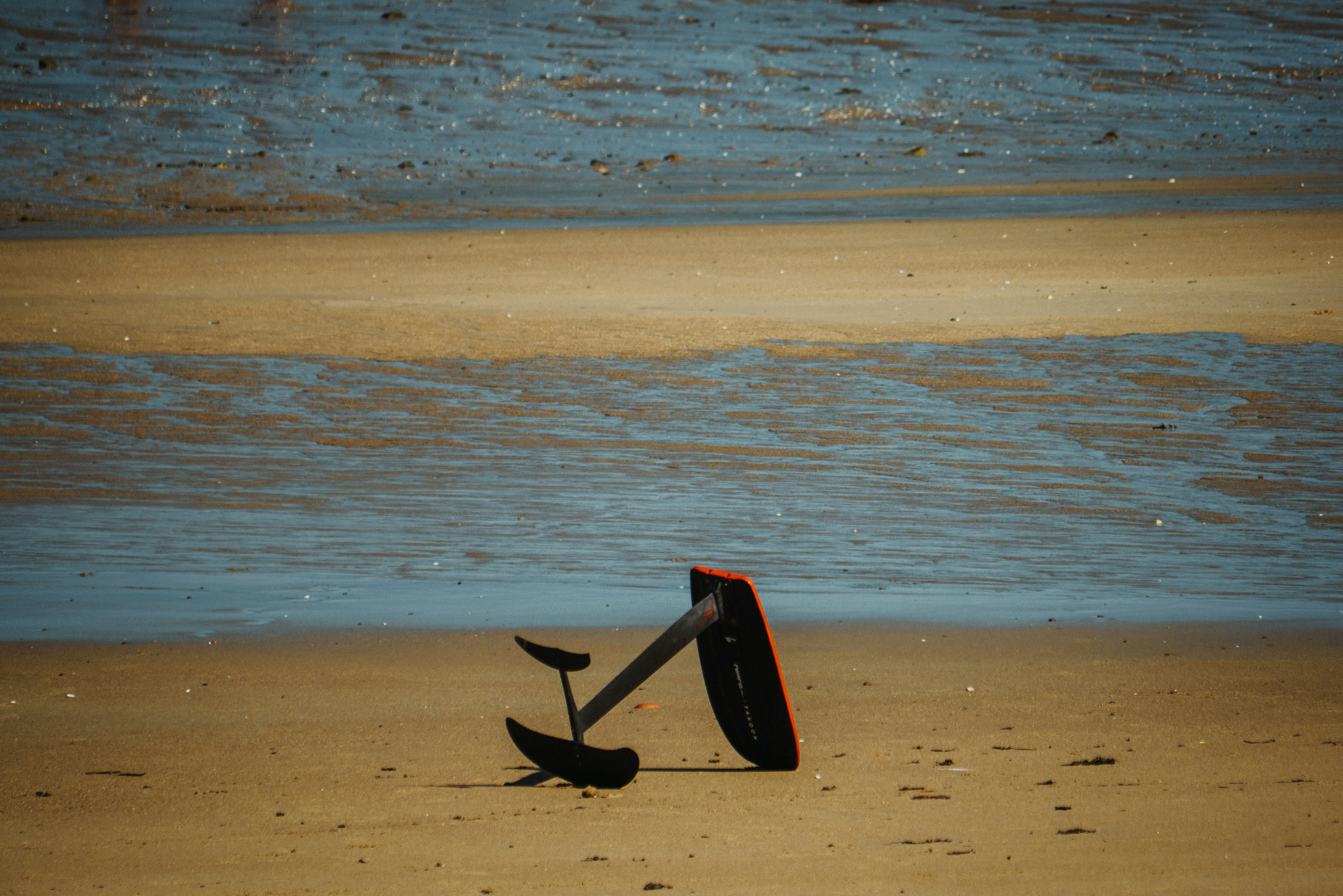 A shovel laying on a beach next to the ocean