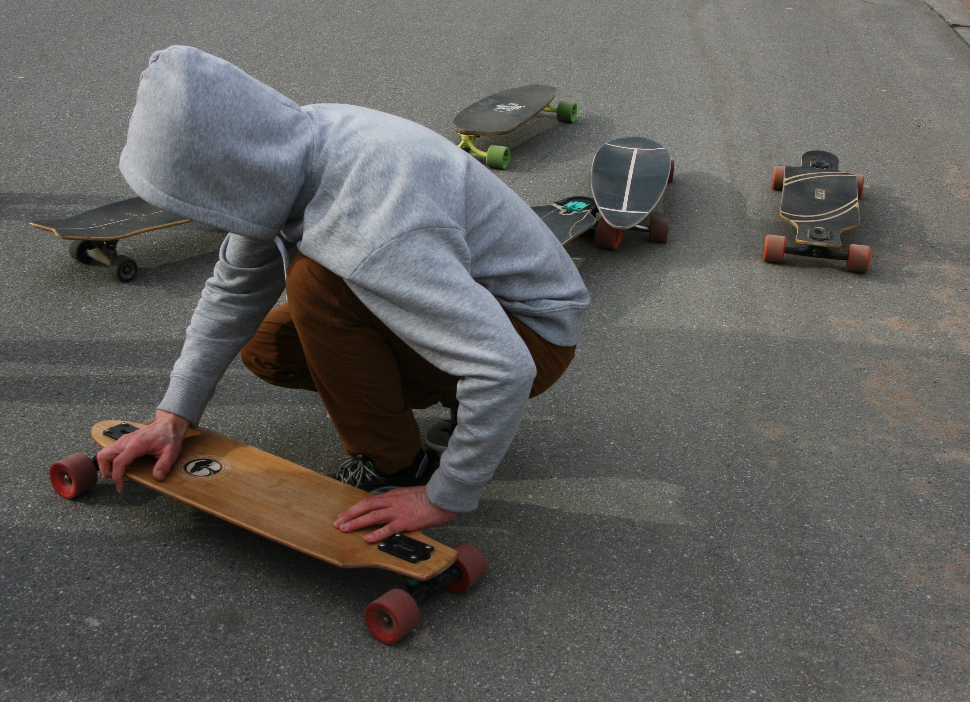 A person kneeling down on a skateboard in the street