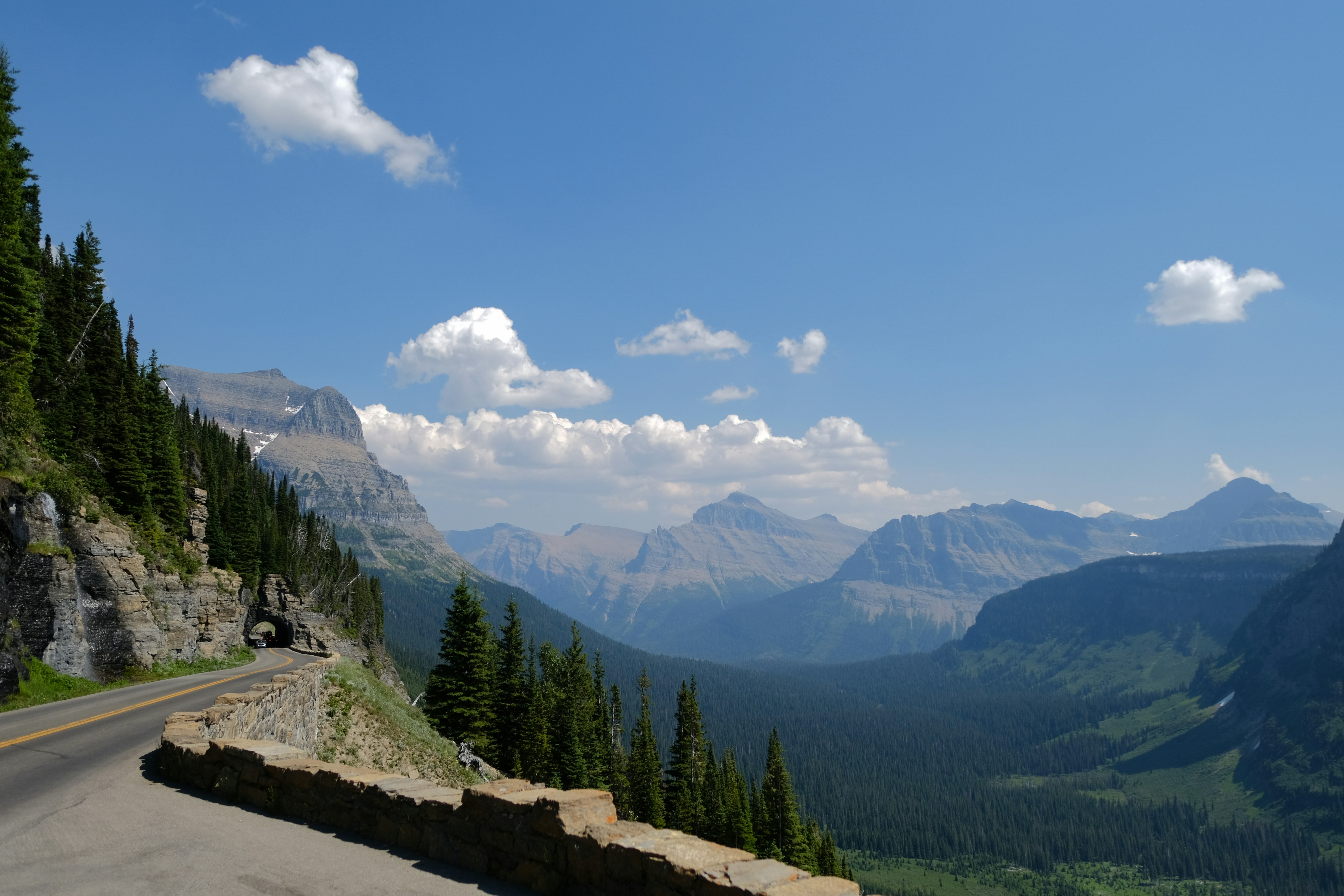 A scenic view of a mountain road with trees and mountains in the background