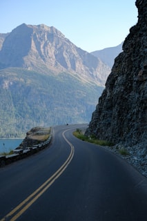A car driving down a road next to a mountain