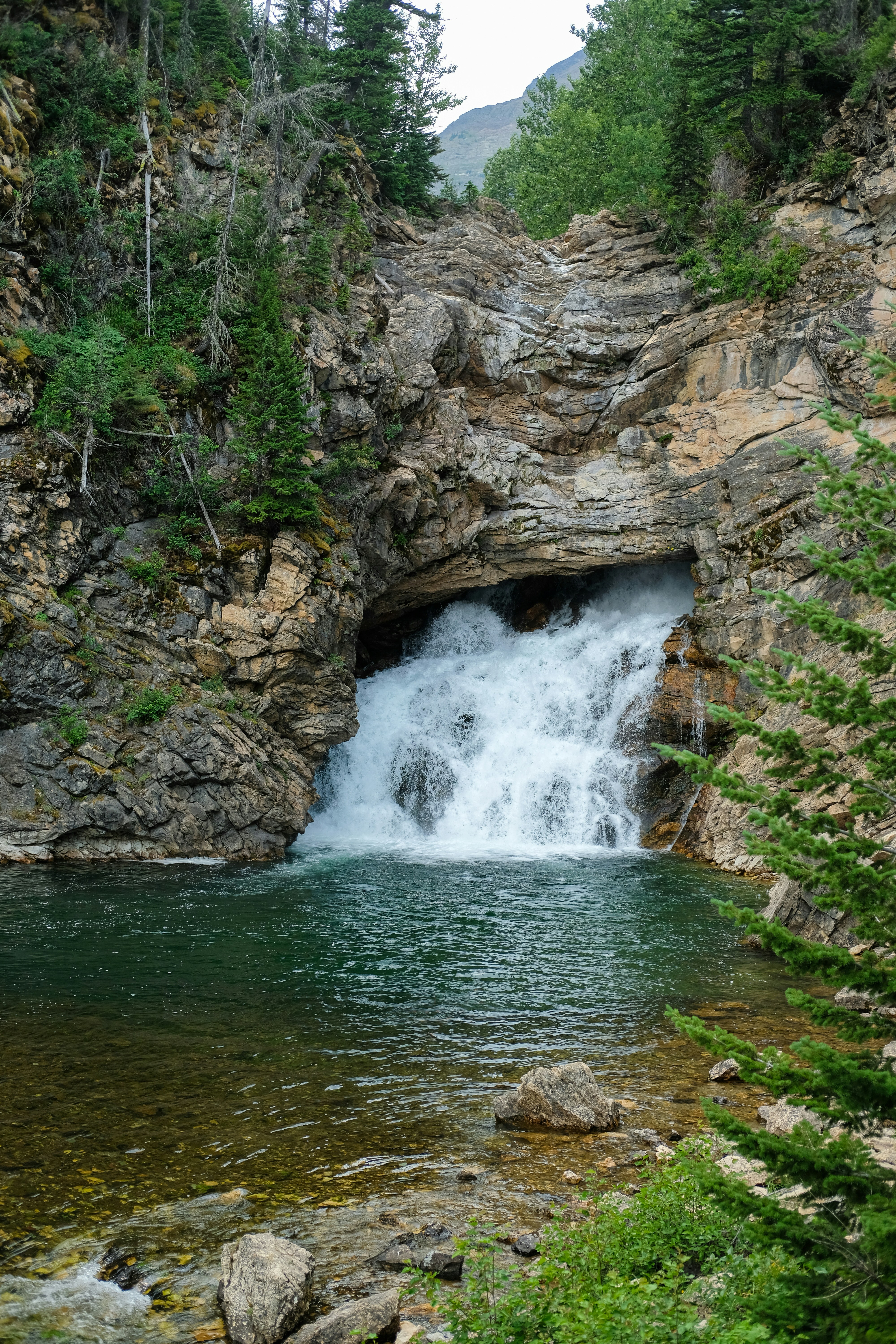 A small waterfall is coming out of a cave