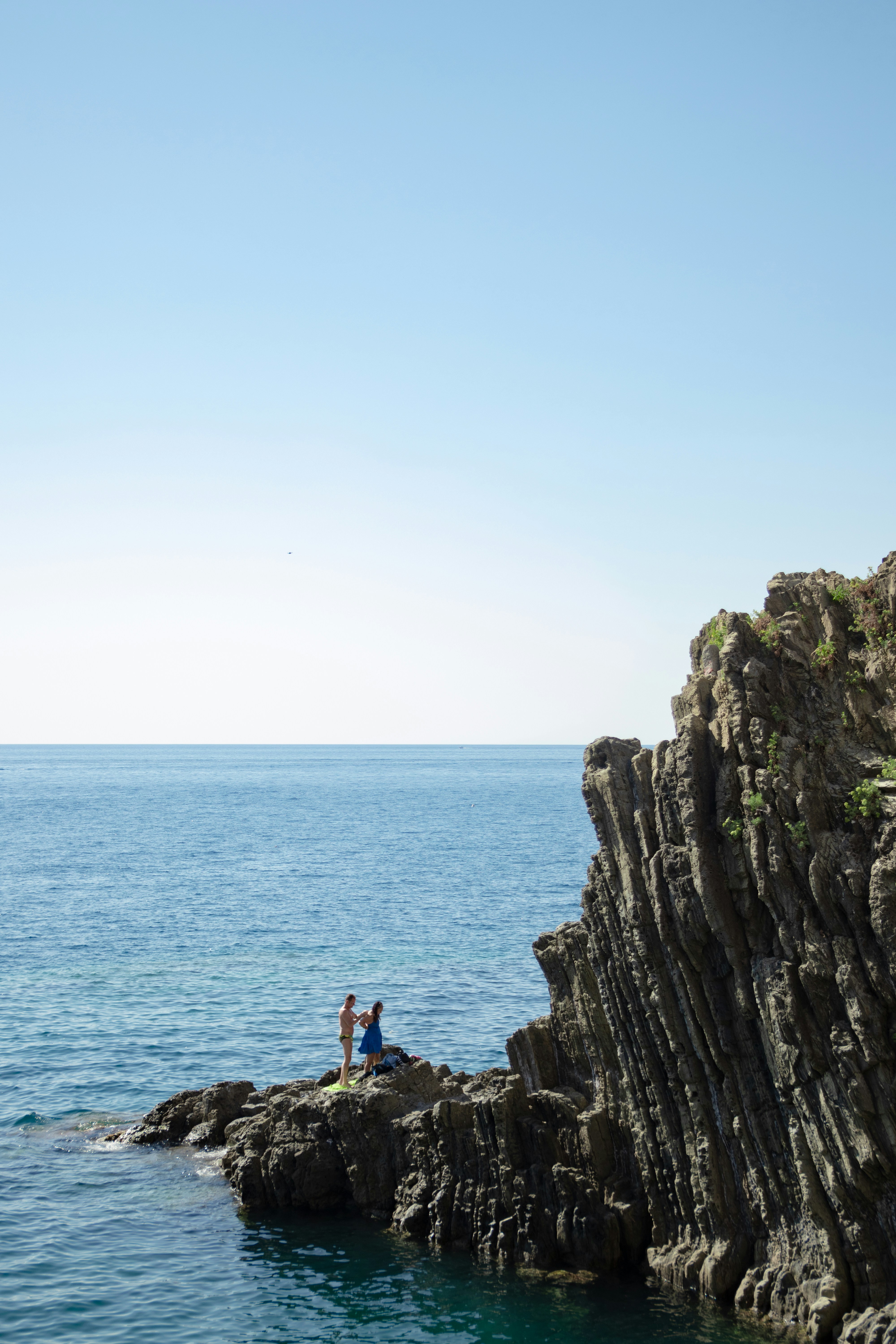 A couple of people standing on top of a rocky cliff