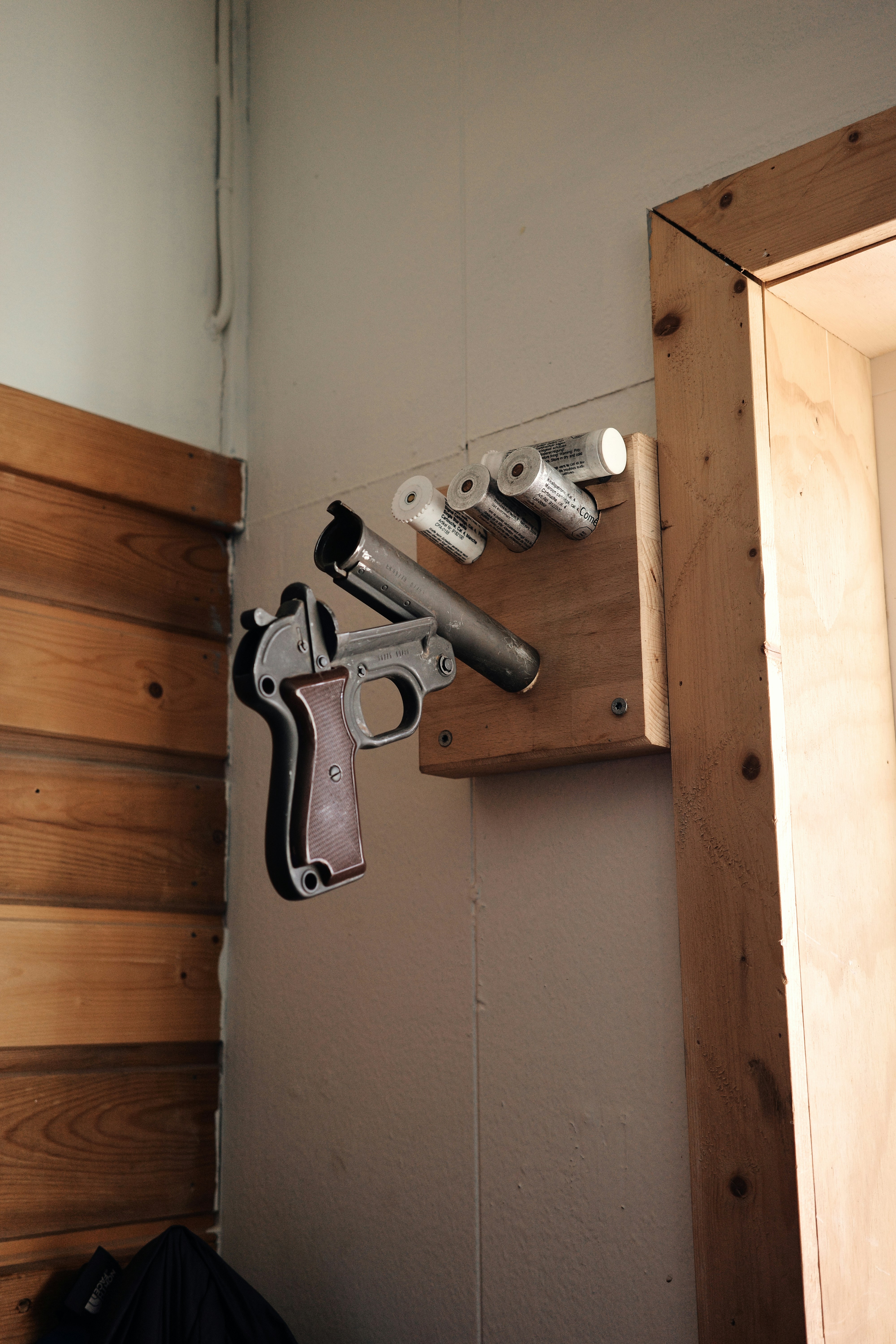 A wooden wall with a gun and two revolvers on it