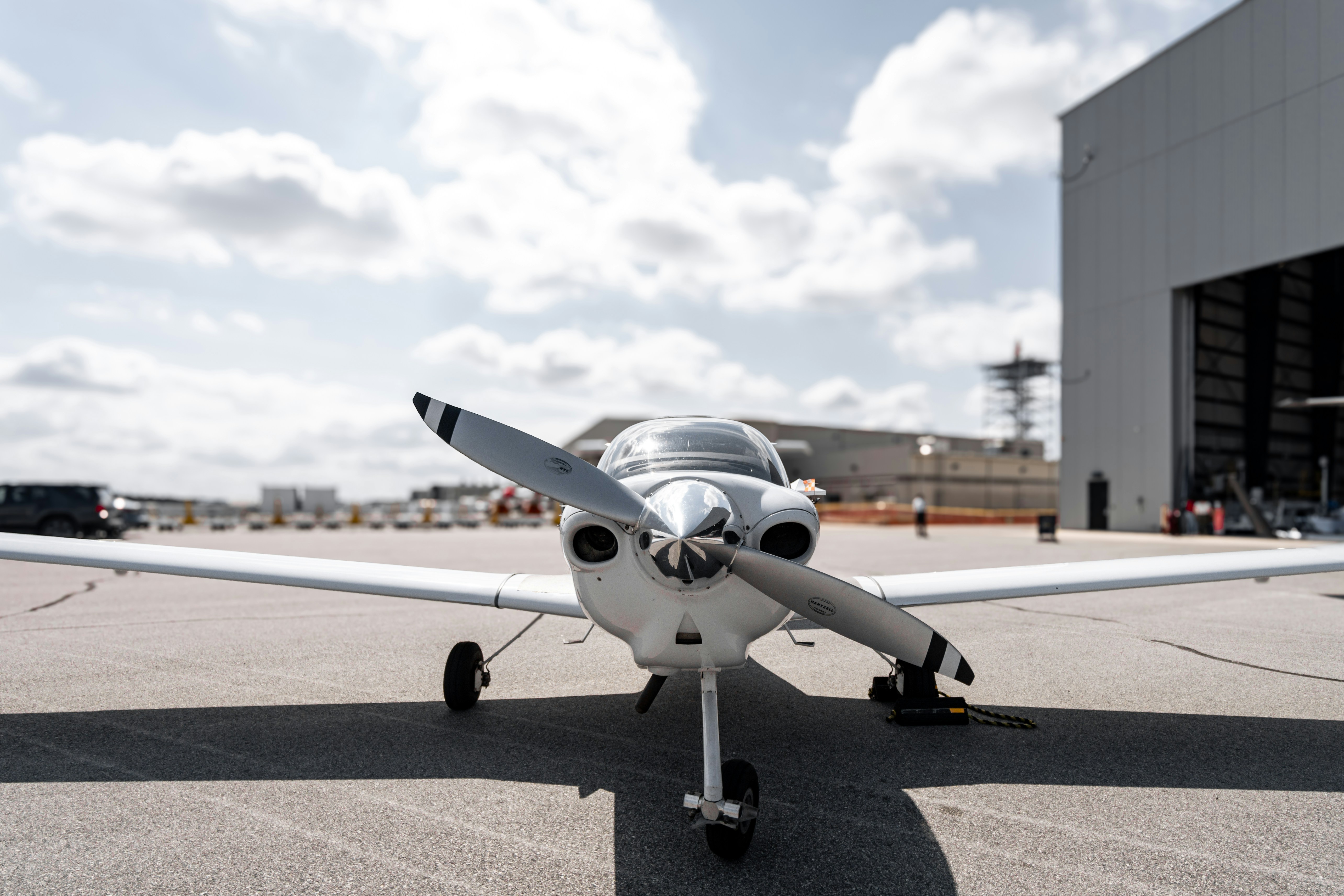 A small airplane parked in front of a hangar, 