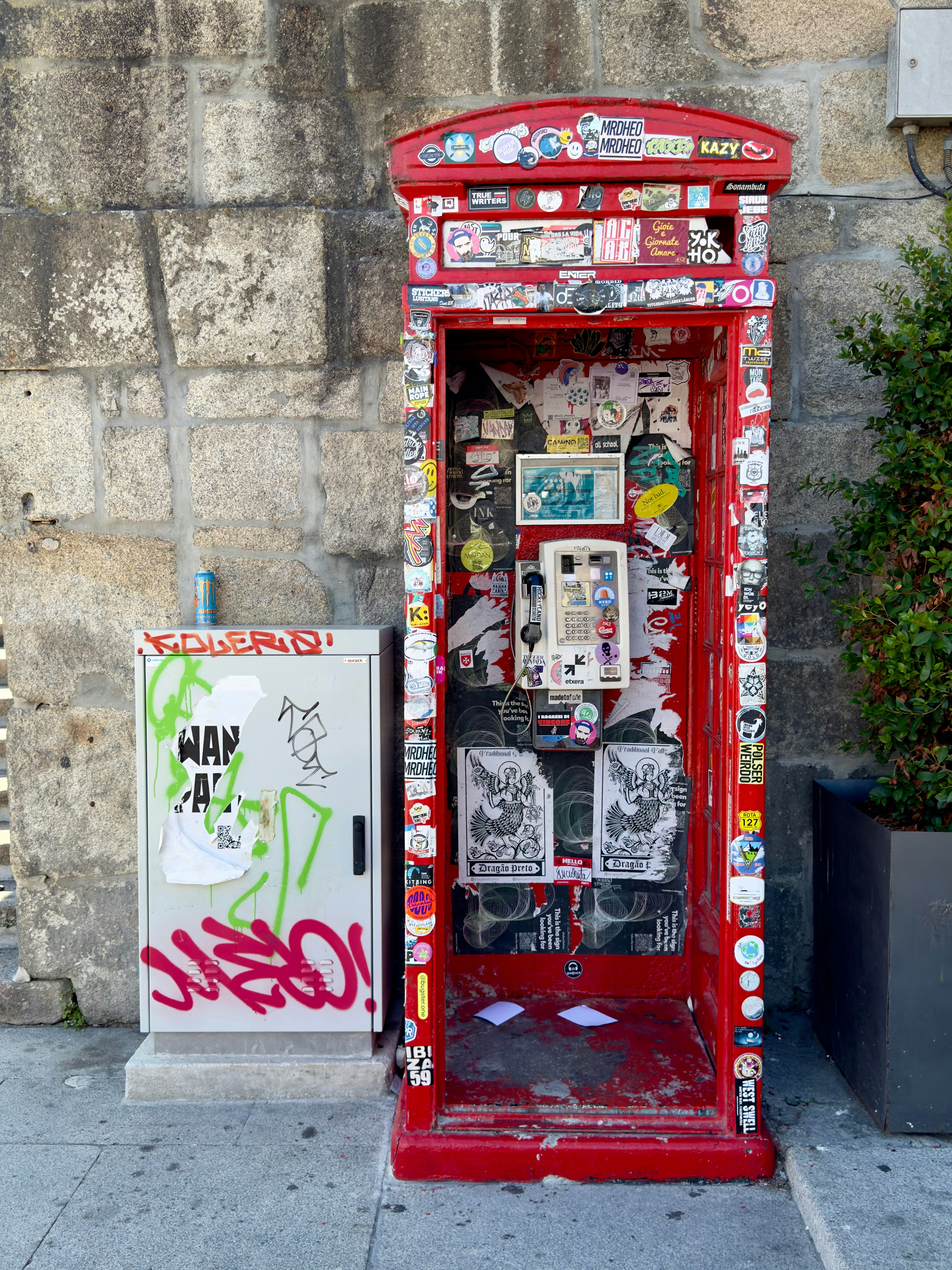 A red phone booth sitting on the side of a street