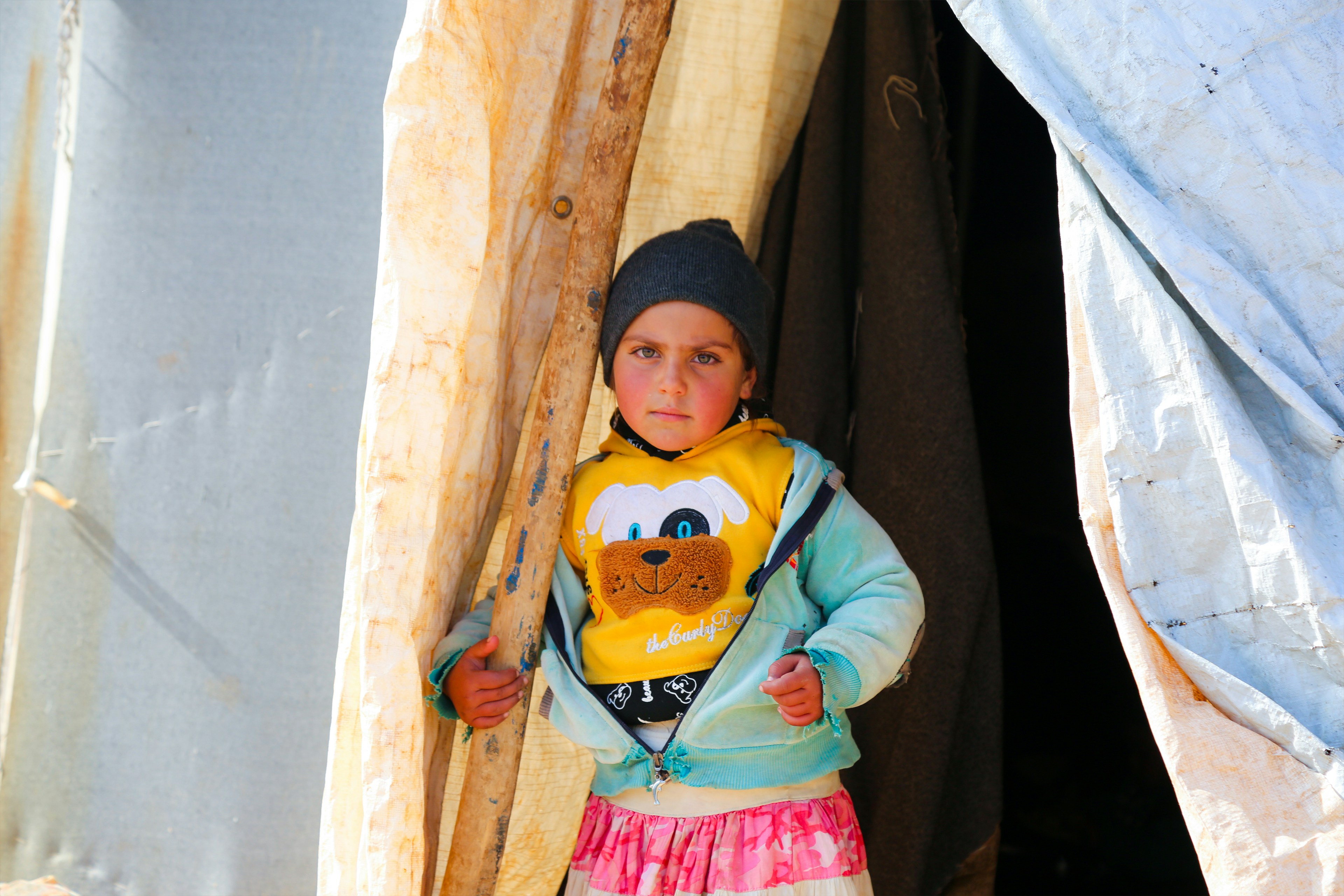 A young girl standing in front of a tent