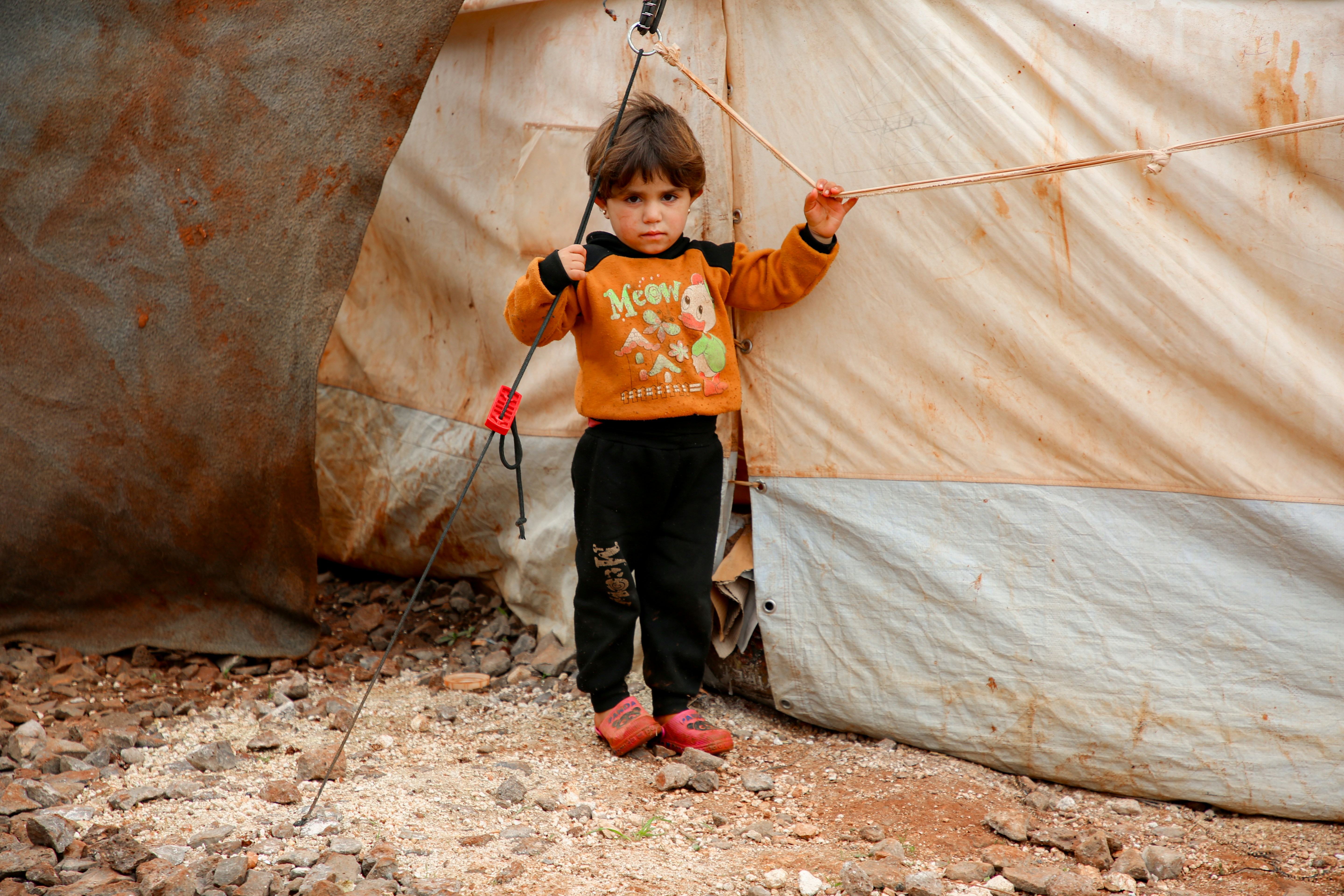 A young boy standing in front of a tent