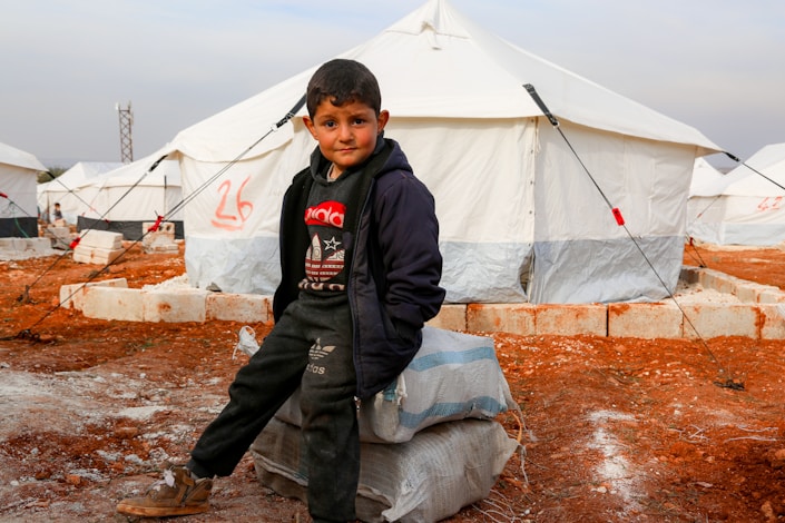 A young boy standing in front of a tent