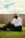 A man sitting on the grass using a cell phone