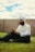 A man sitting on the grass using a cell phone