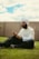 A man sitting on the grass using a cell phone