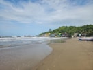 A beach with a boat on the sand and trees in the background