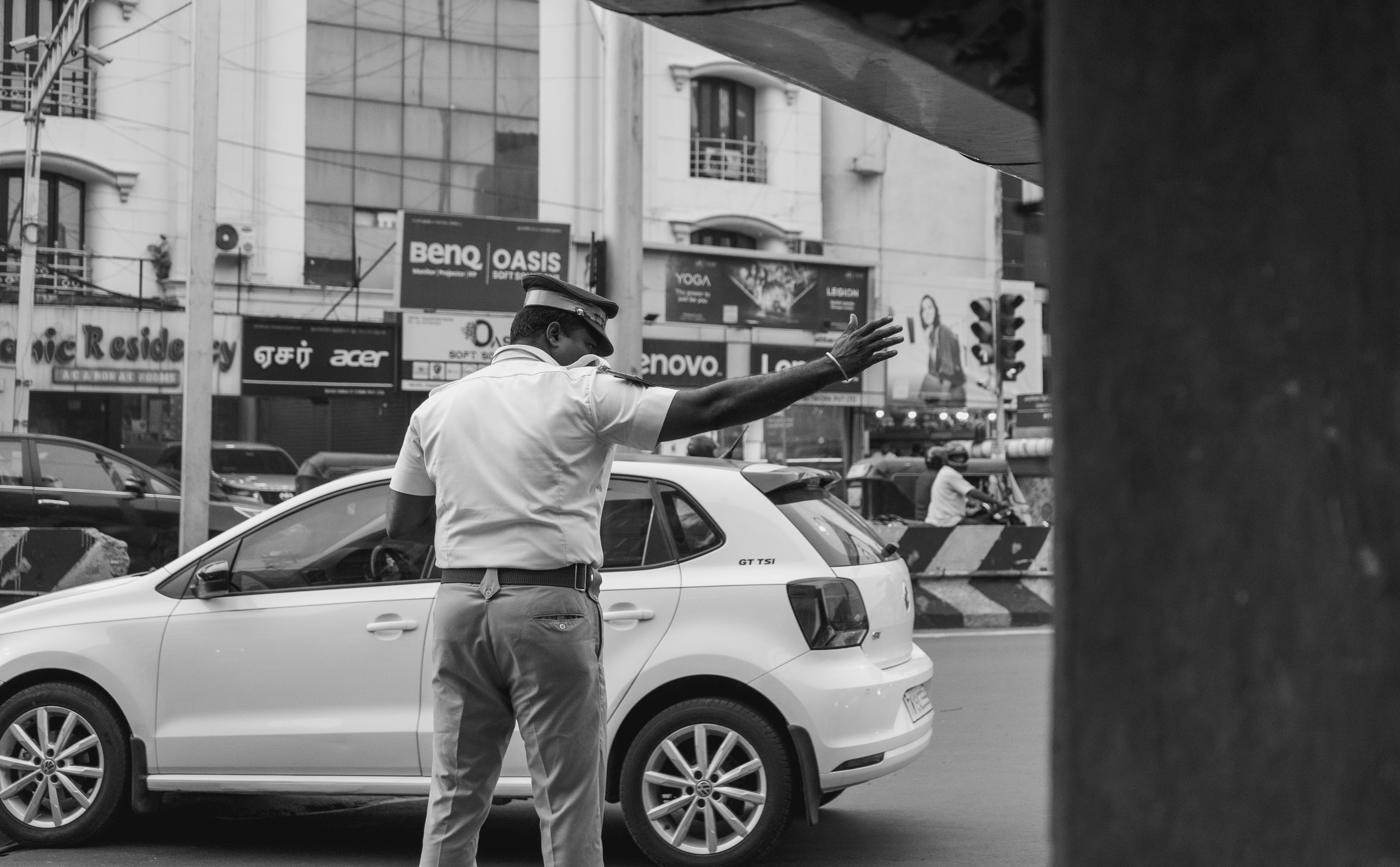 A black and white photo of a man standing in front of a car