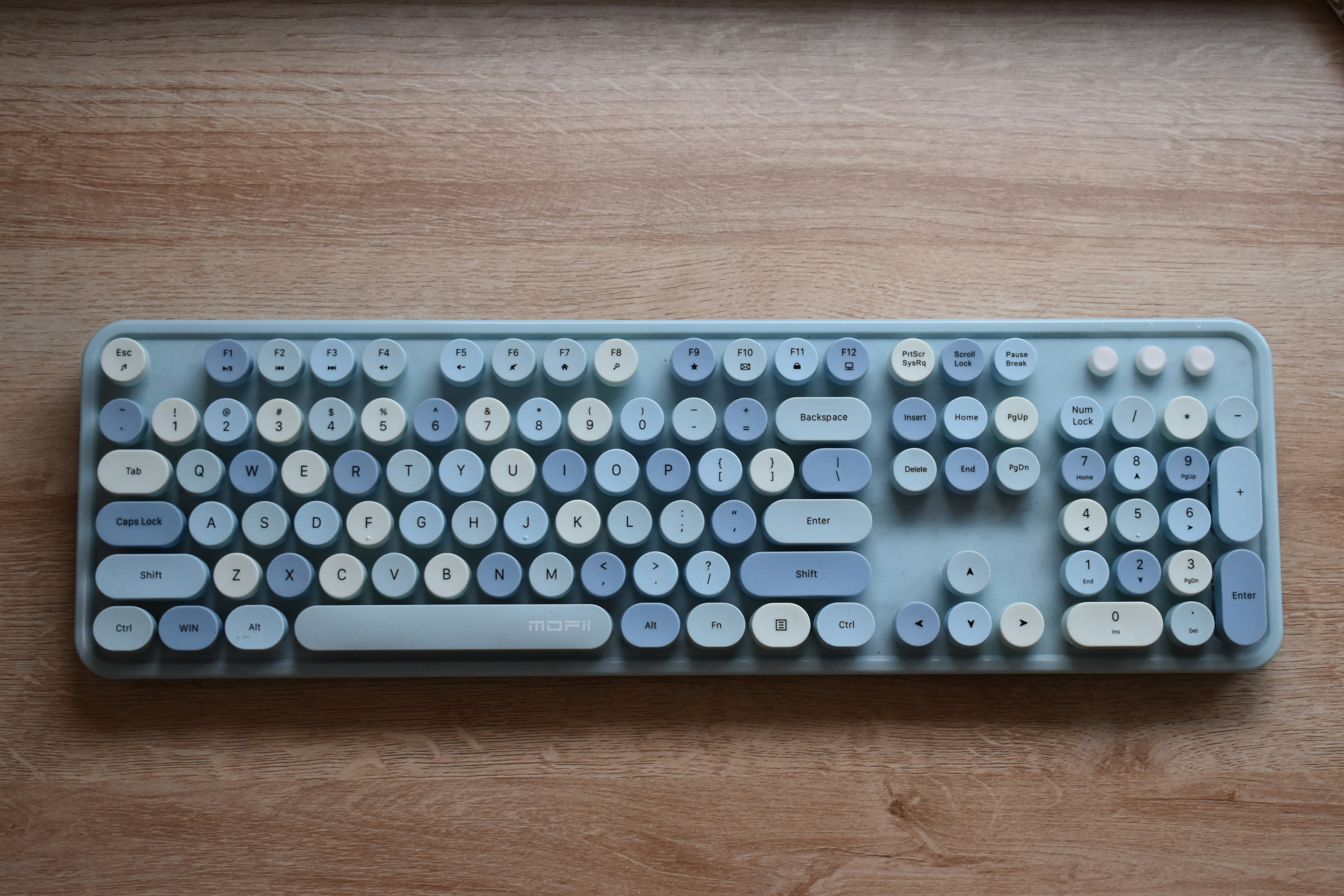 A computer keyboard sitting on top of a wooden table