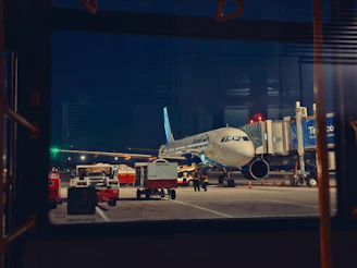 An airplane is parked at an airport at night