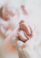 A person holding a baby's foot in their hands